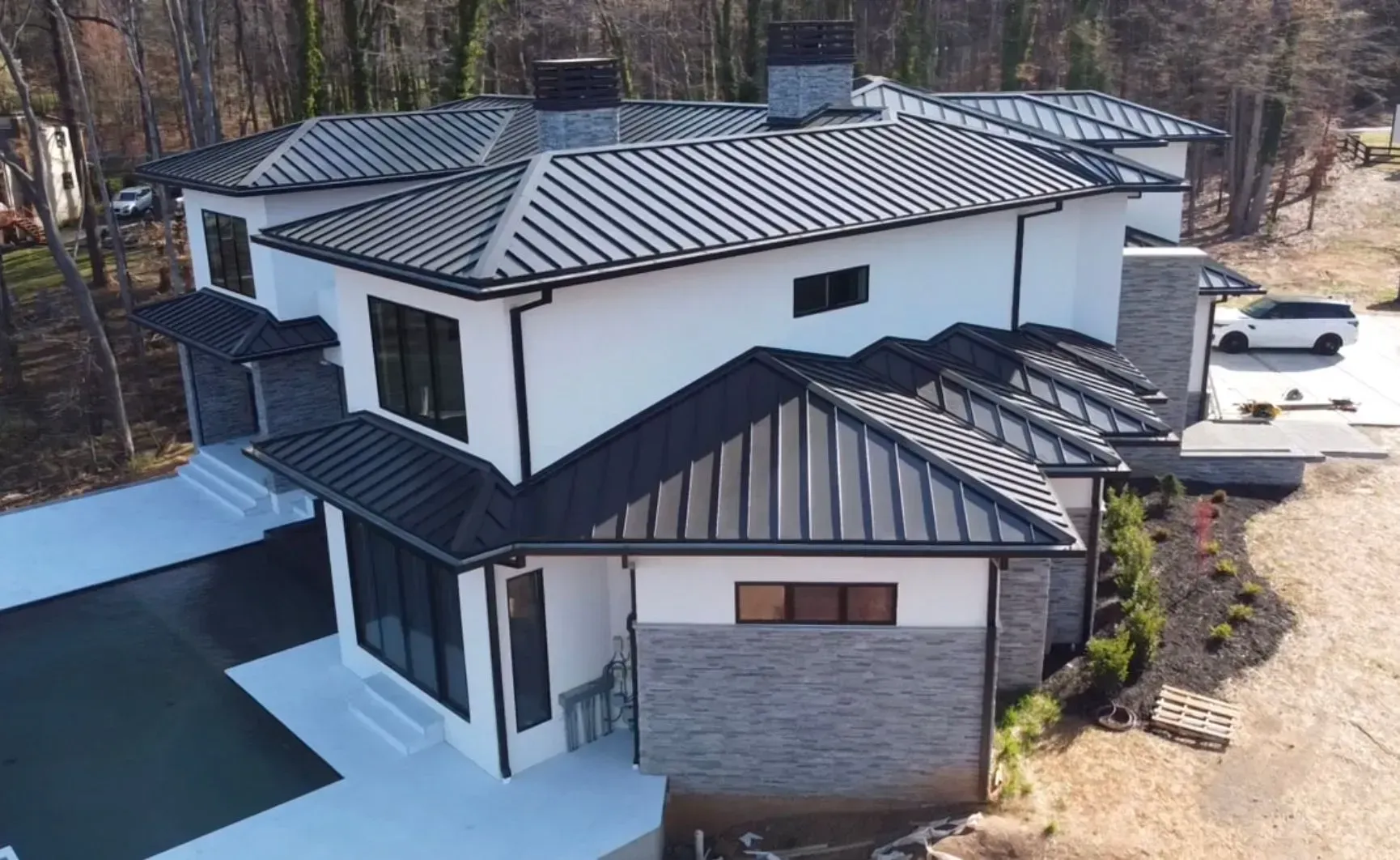 An aerial view of a large white house with a black roof.