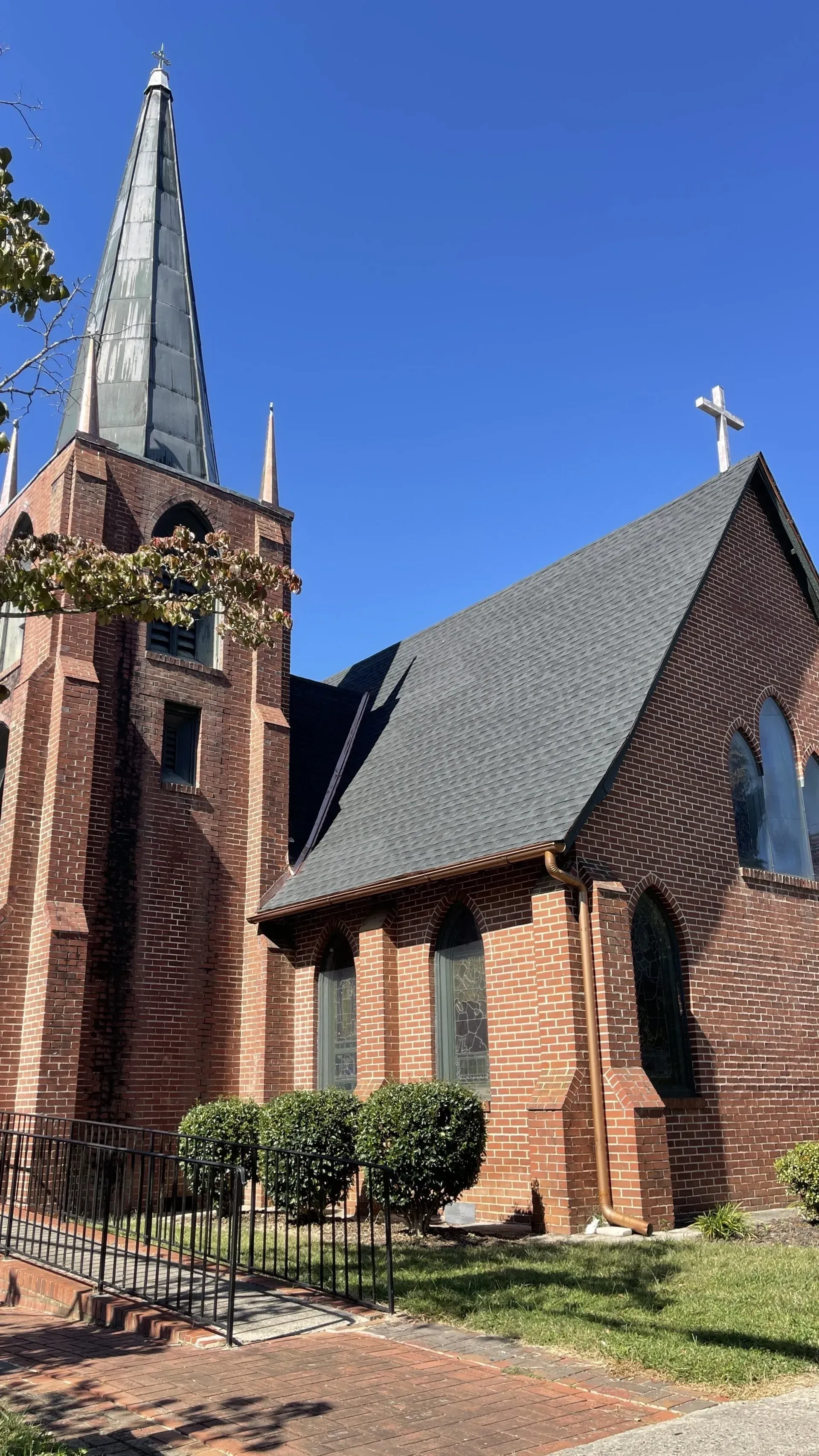 A large brick church with a steeple and a cross on top of it.