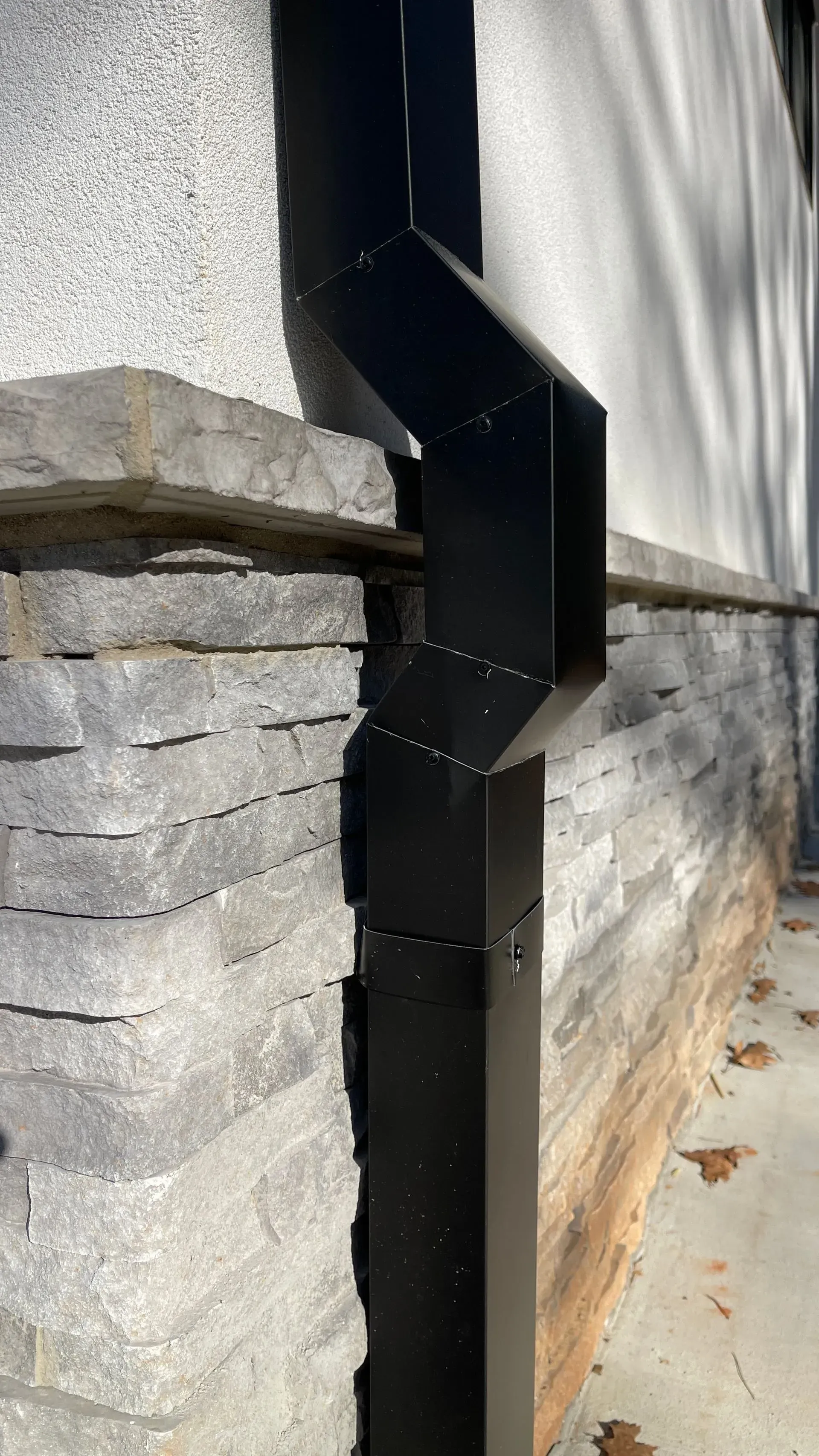 A black drainpipe is attached to the side of a building.