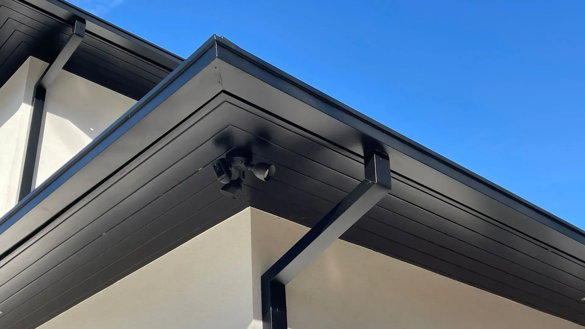 A house with a black gutter and a blue sky in the background