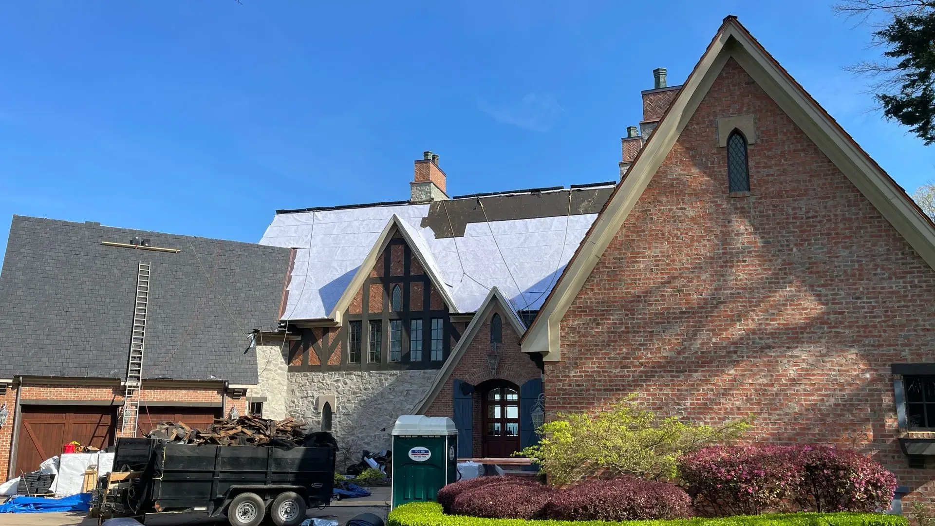 A large brick house with a dumpster in front of it.