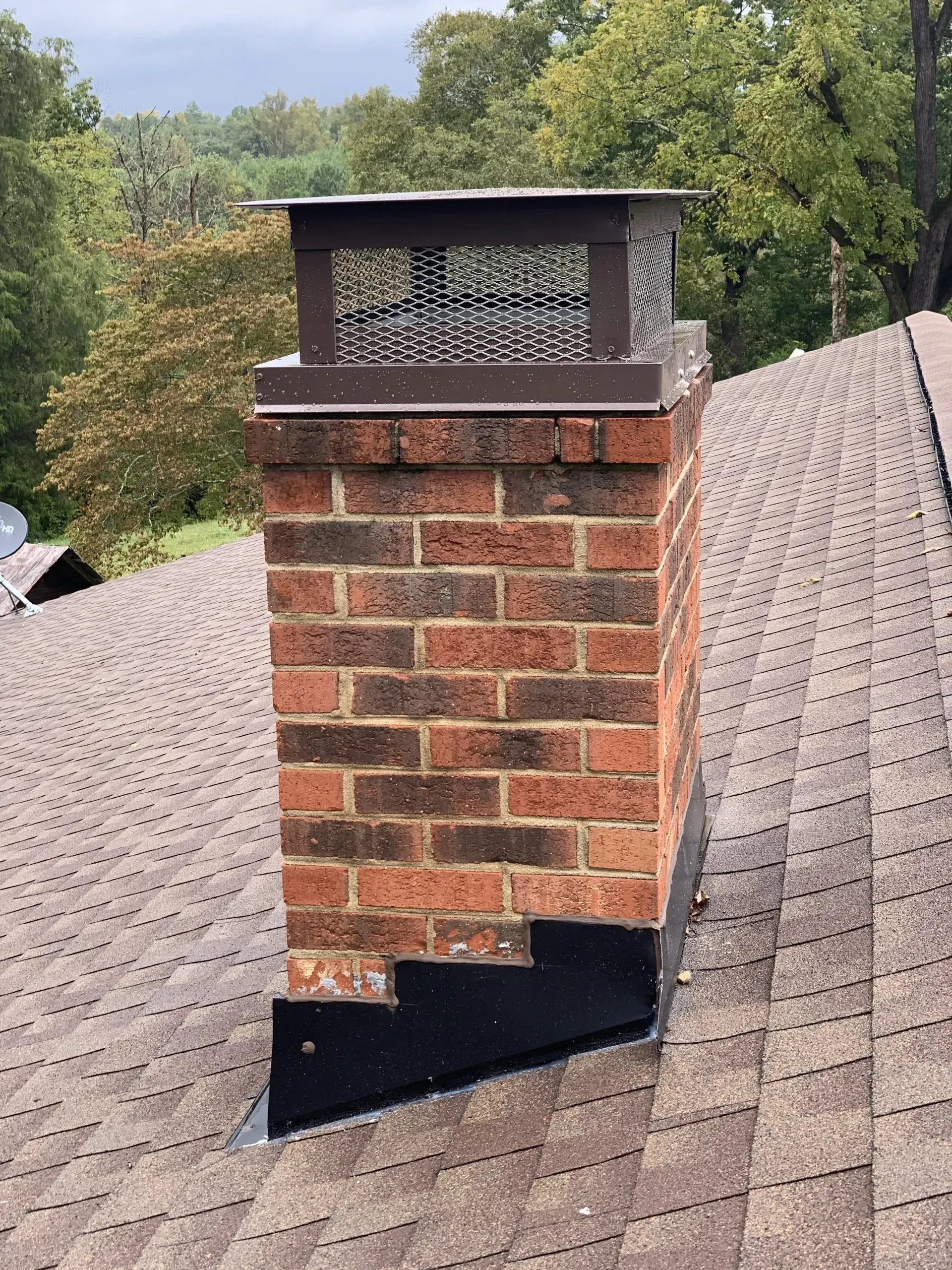 A brick chimney is sitting on top of a roof.