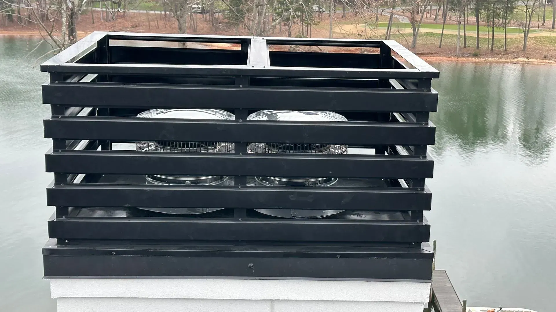 A black and white wooden structure is sitting on top of a dock next to a body of water.