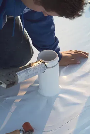 A man in a blue jacket is working on a roof