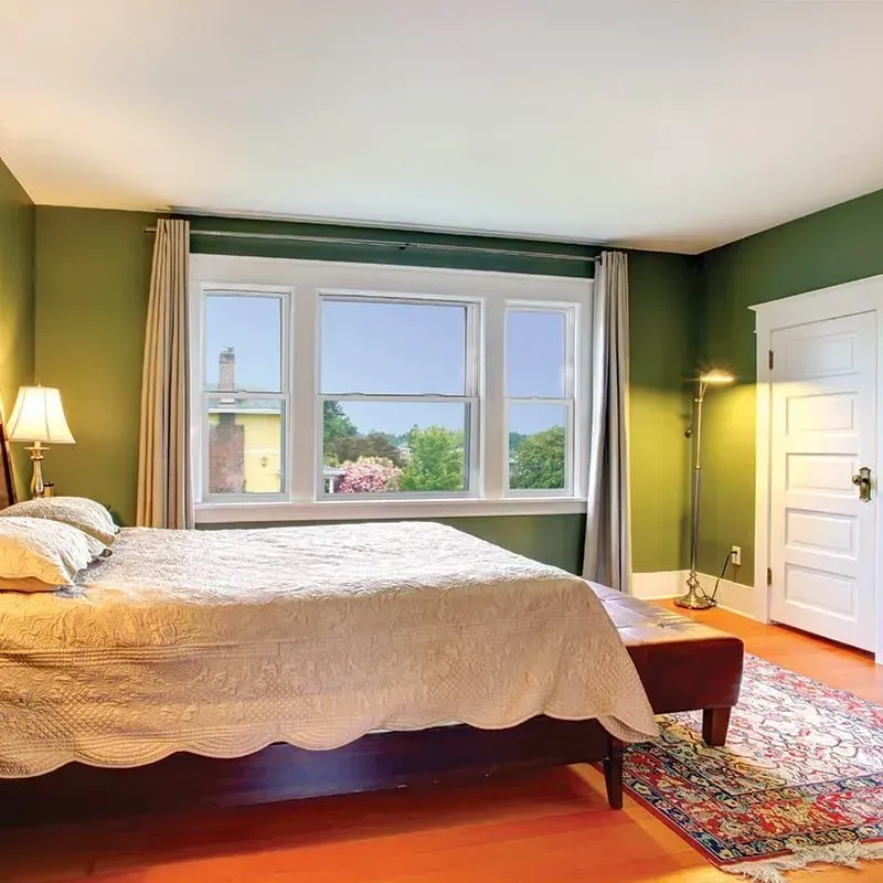 A bedroom with green walls and a king size bed