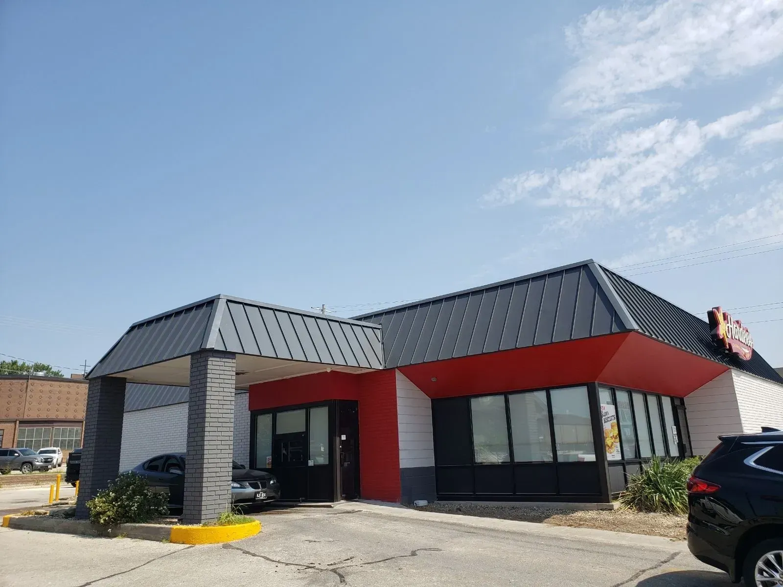 A black car is parked in front of a fast food restaurant.