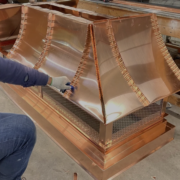 A man is working on a copper chimney hood