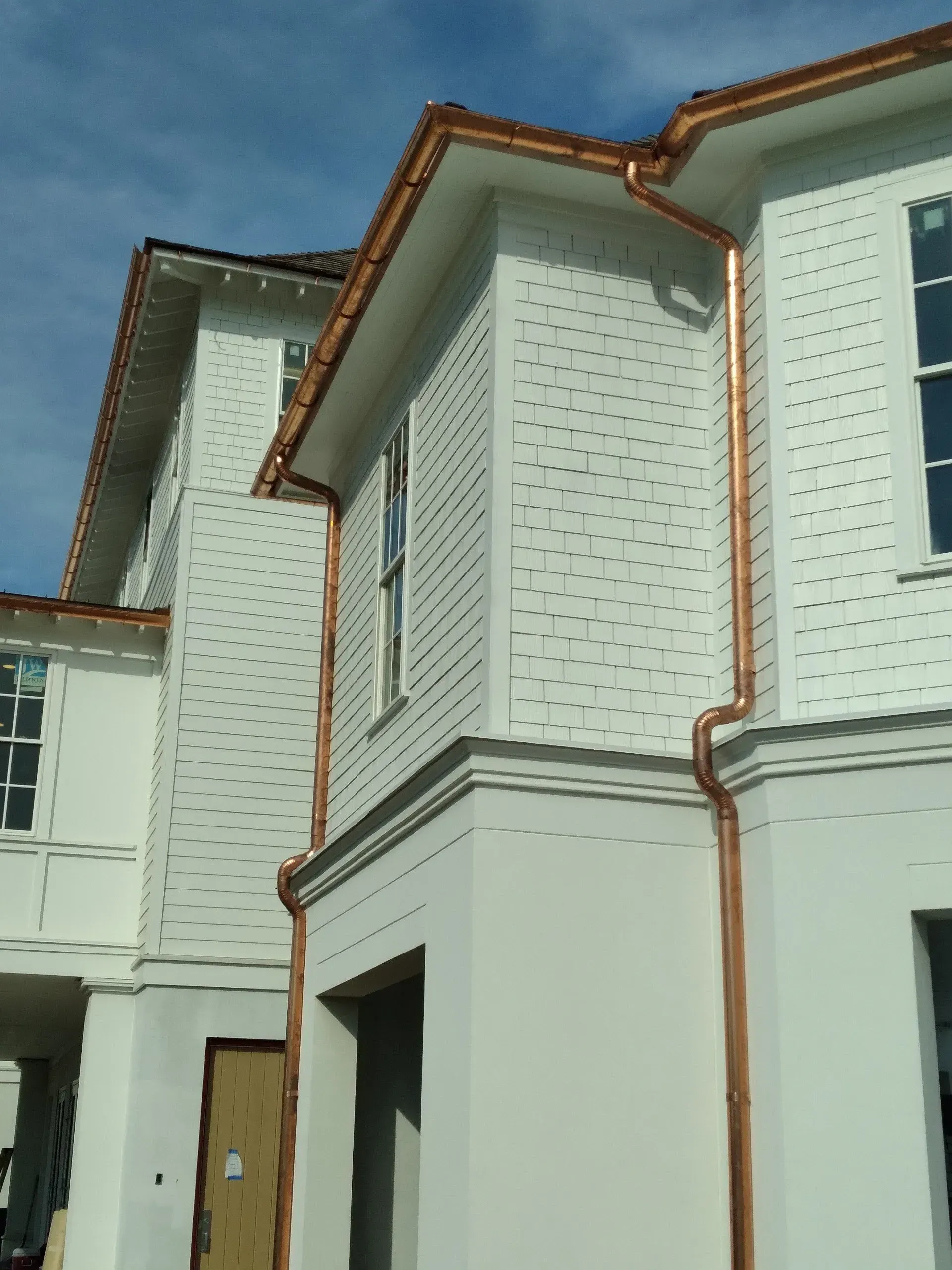 A white house with copper gutters on the side