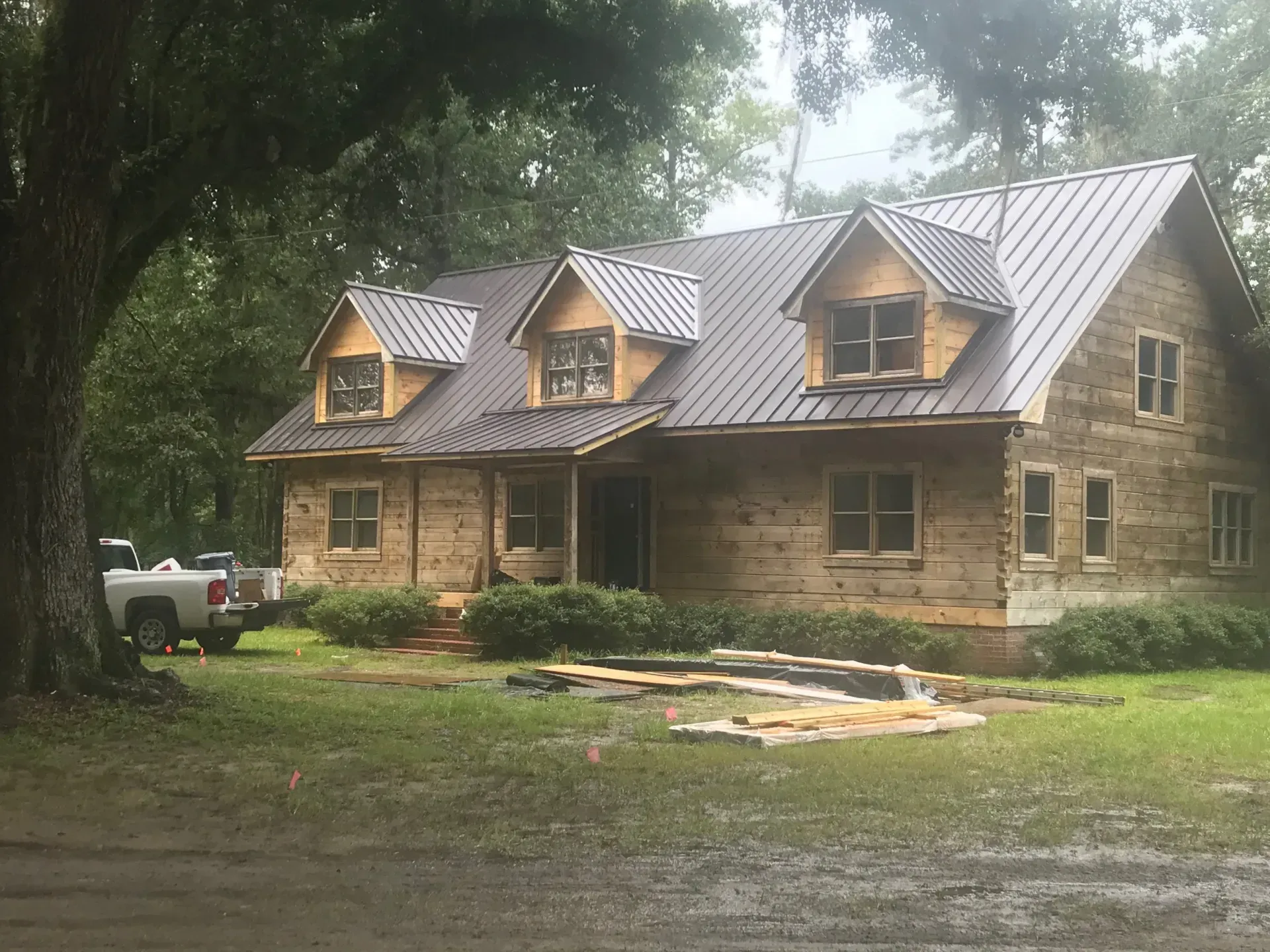A large log cabin with a metal roof is being built.