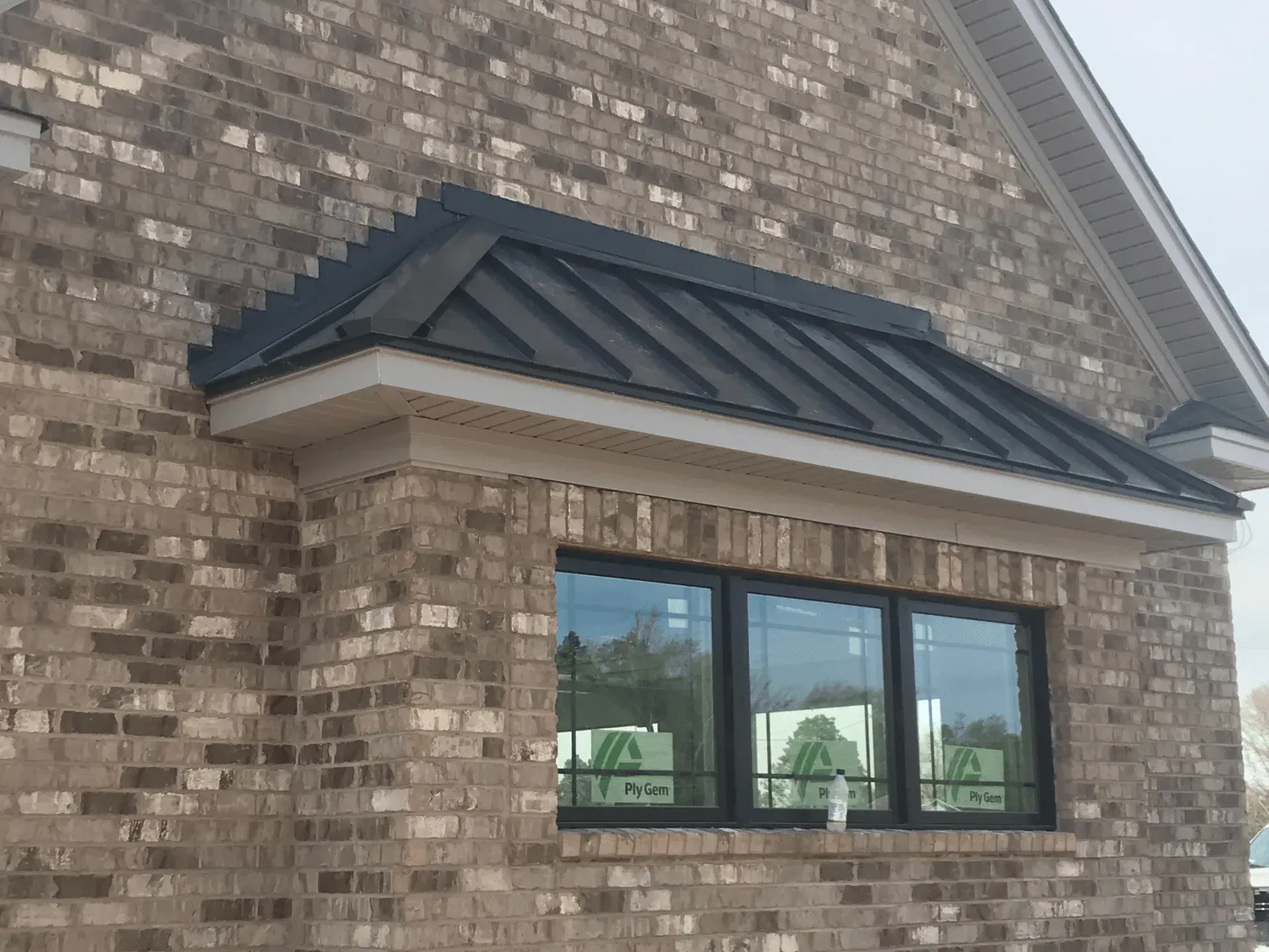 A brick building with a window and a black roof.