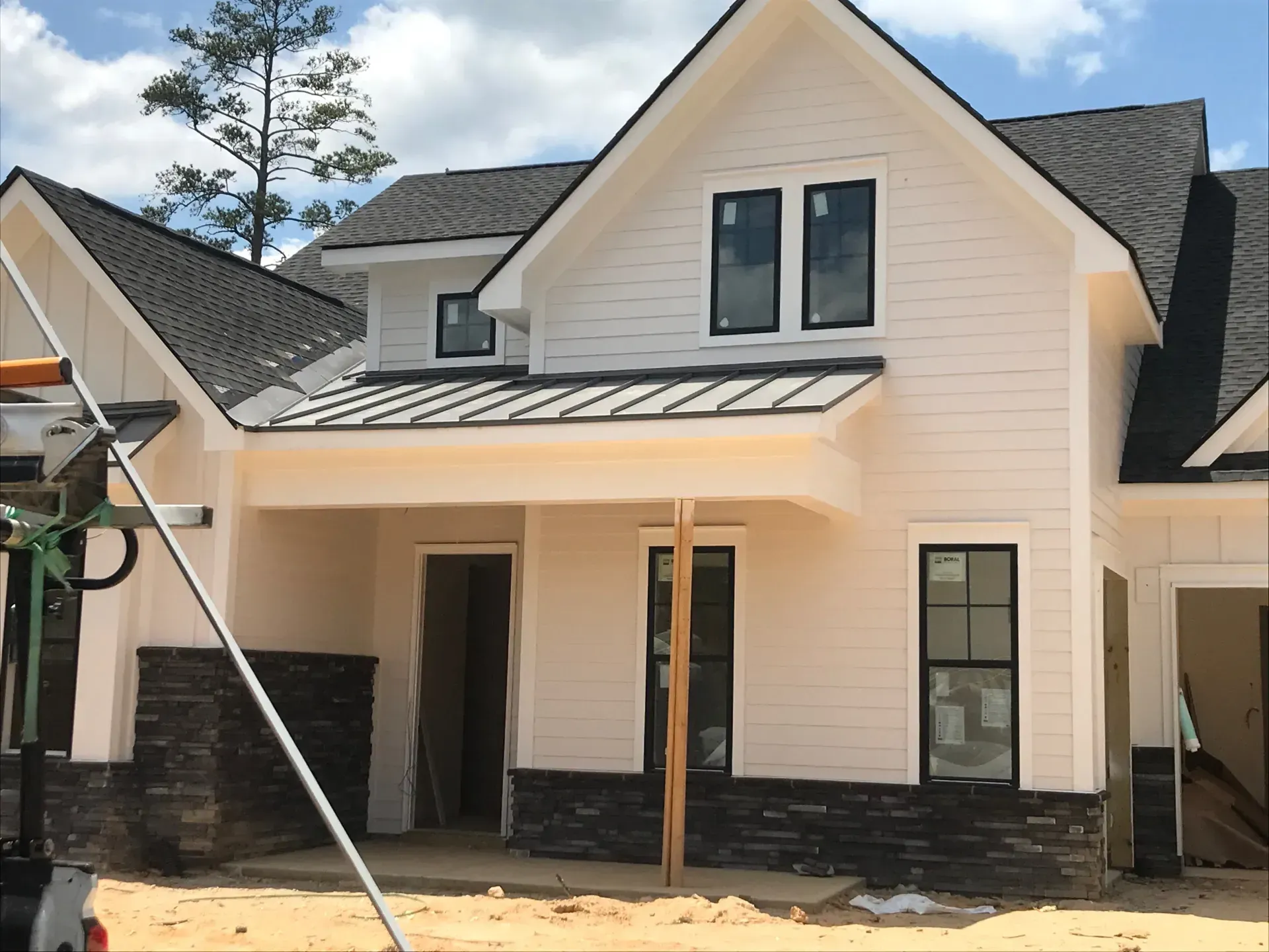 A white house with a black roof is under construction
