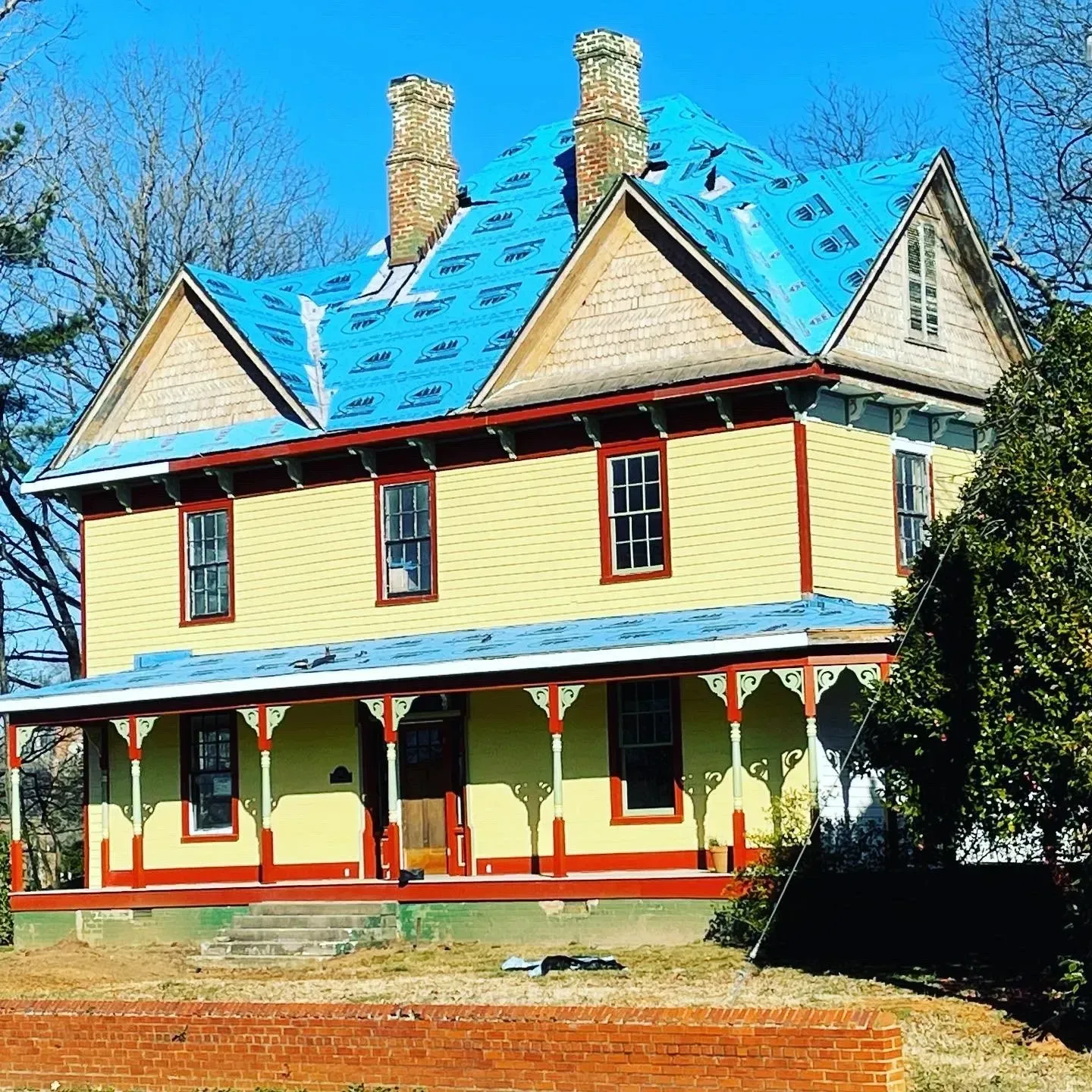 A yellow house with a blue roof and a porch
