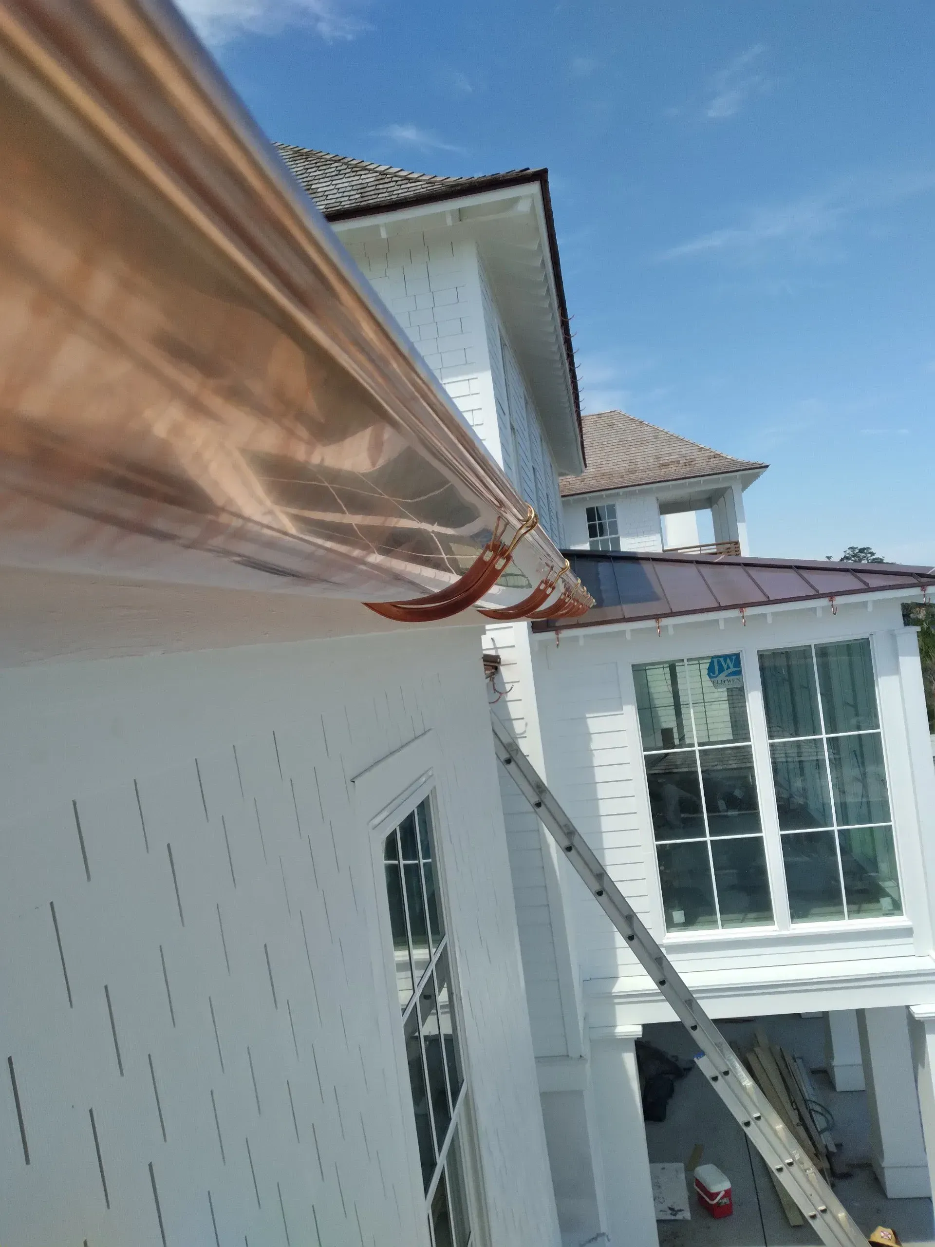 A white house with a copper gutter on the side