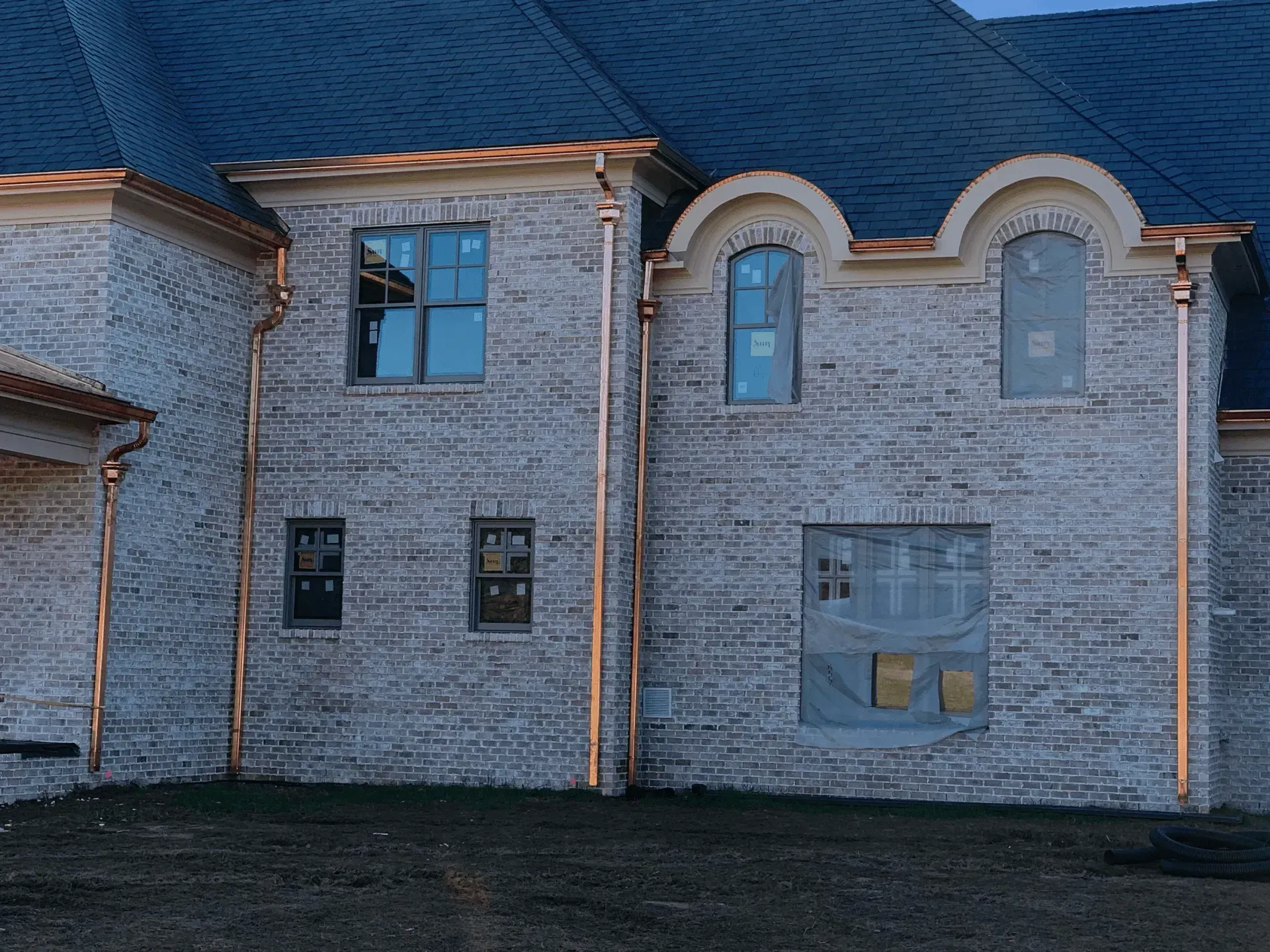 A white brick house with copper gutters and a blue roof