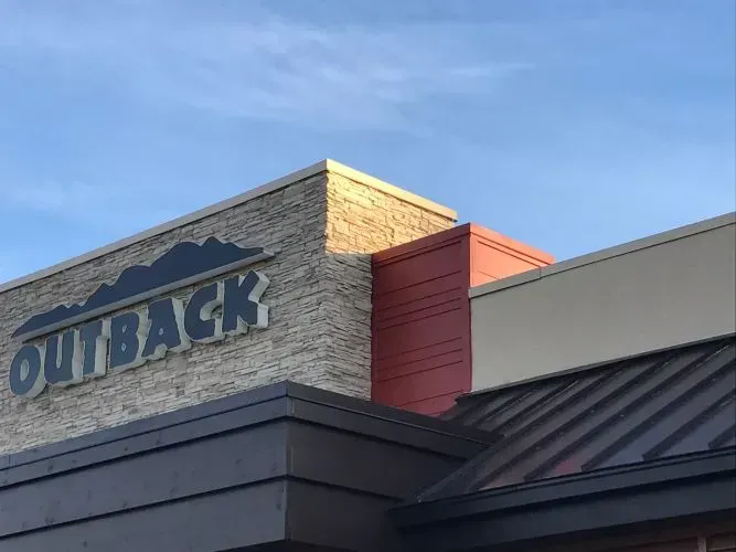 The outside of an outback restaurant with a blue sky in the background