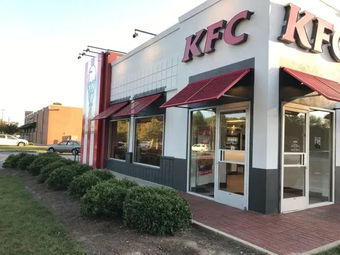 The outside of a kfc restaurant with a red awning