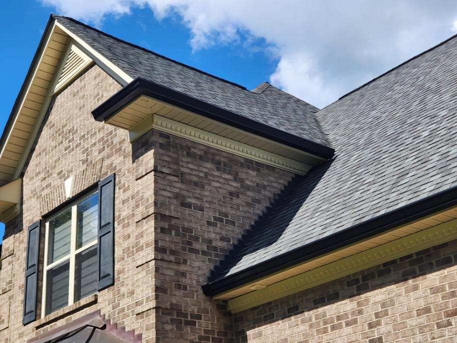 A brick house with a gray roof and black shutters.