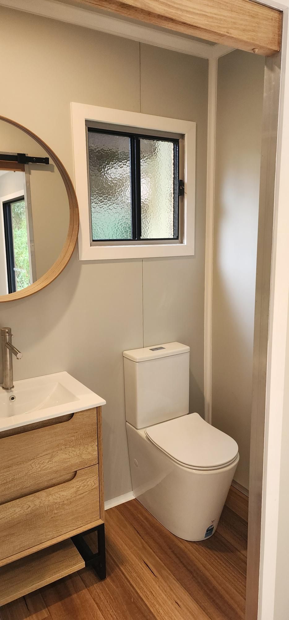 A Bathroom with A Toilet , Sink , Mirror and Window — Alternative Modular Home In Toowoomba City, QLD