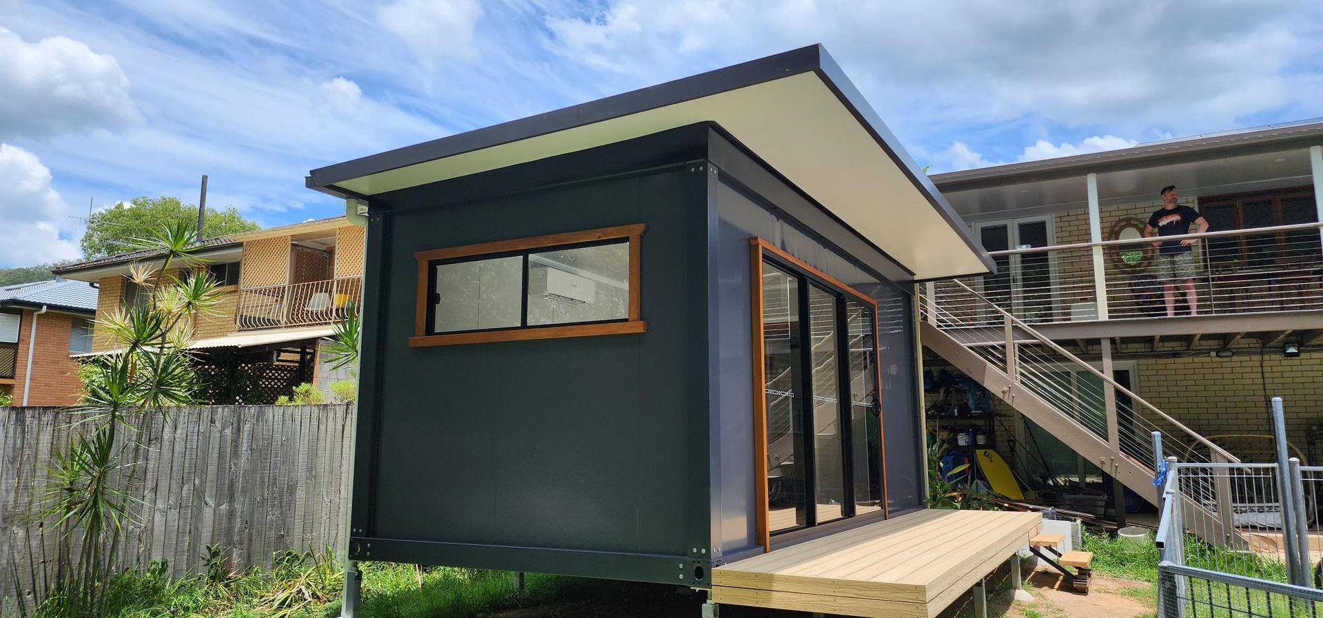 A Small House Is Sitting on Top of A Wooden Deck in Front of A House — Alternative Modular Home In Toowoomba City, QLD