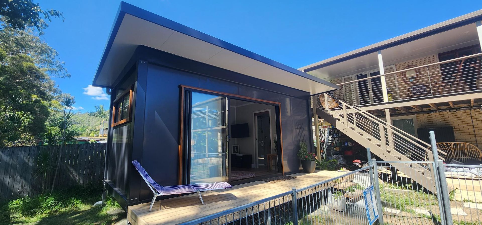 A Small House with Stairs Leading up To It Is Sitting Next to A Large House — Alternative Modular Home In Toowoomba City, QLD