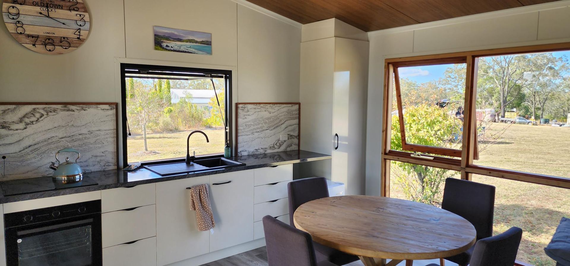 A Kitchen with A Table and Chairs and A Clock on The Wall — Alternative Modular Home In Toowoomba City, QLD