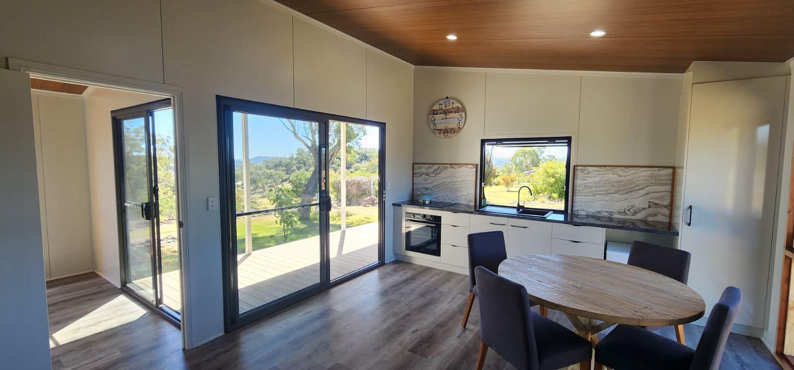 A Kitchen with A Table and Chairs and A Clock on The Wall — Alternative Modular Home In Toowoomba City, QLD