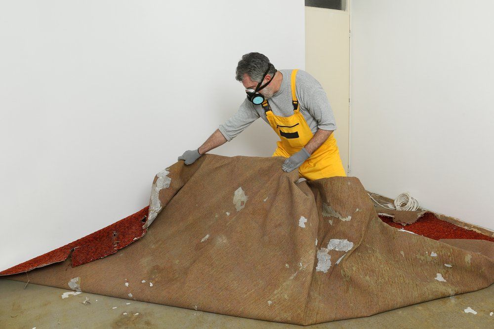 Adult Worker With Protective Mask Removing Old Carpet — Carpet Cleaning In Tuncurry, NSW