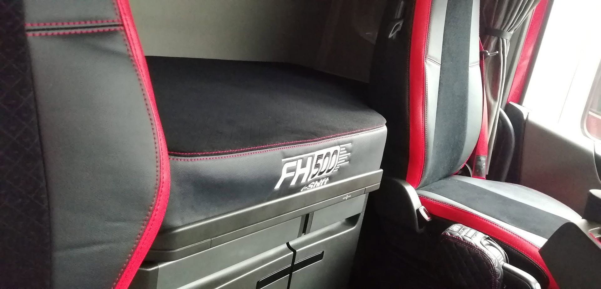 Asientos de cabina de camión negros y rojos con caja de almacenamiento y luz de ventana.