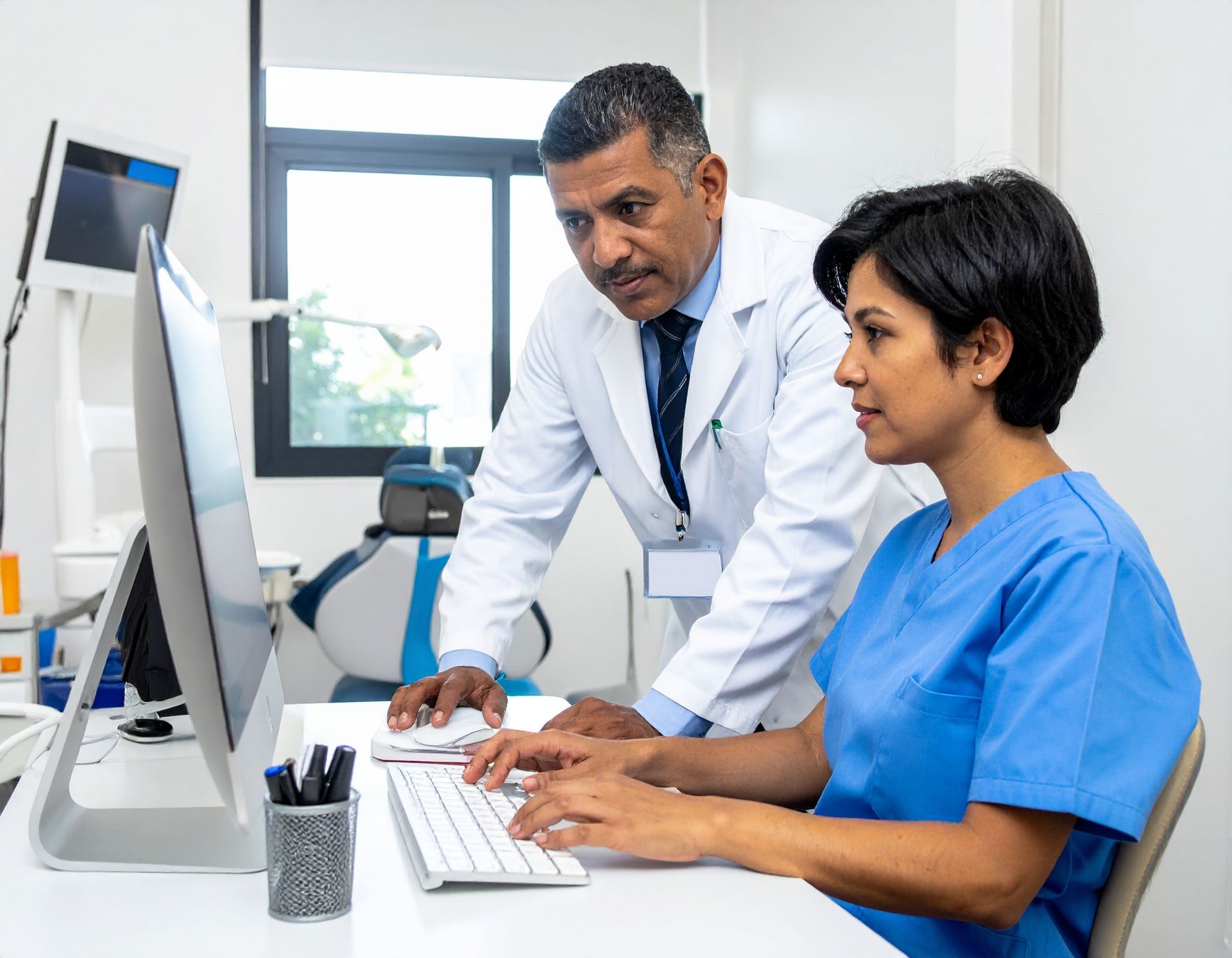 Doctor and nurse reviewing patient data on a computer in a dental office.