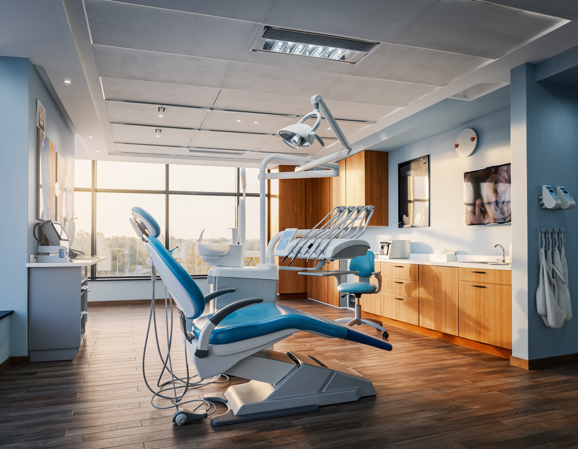 A dental office with blue and white chair, tools, and cabinets. Sunlight streams in from a large window.