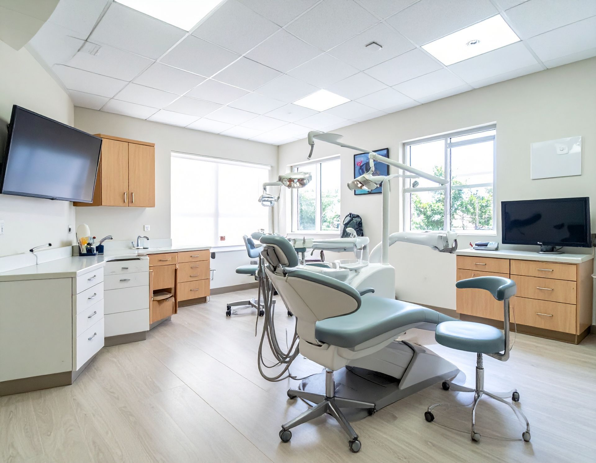 Dental operatory with dental chair, equipment, cabinets, and windows.