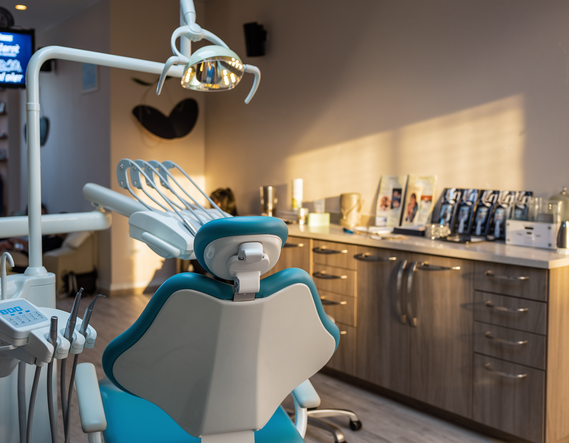 Dental chair in a bright, modern office with tools and a cabinet.