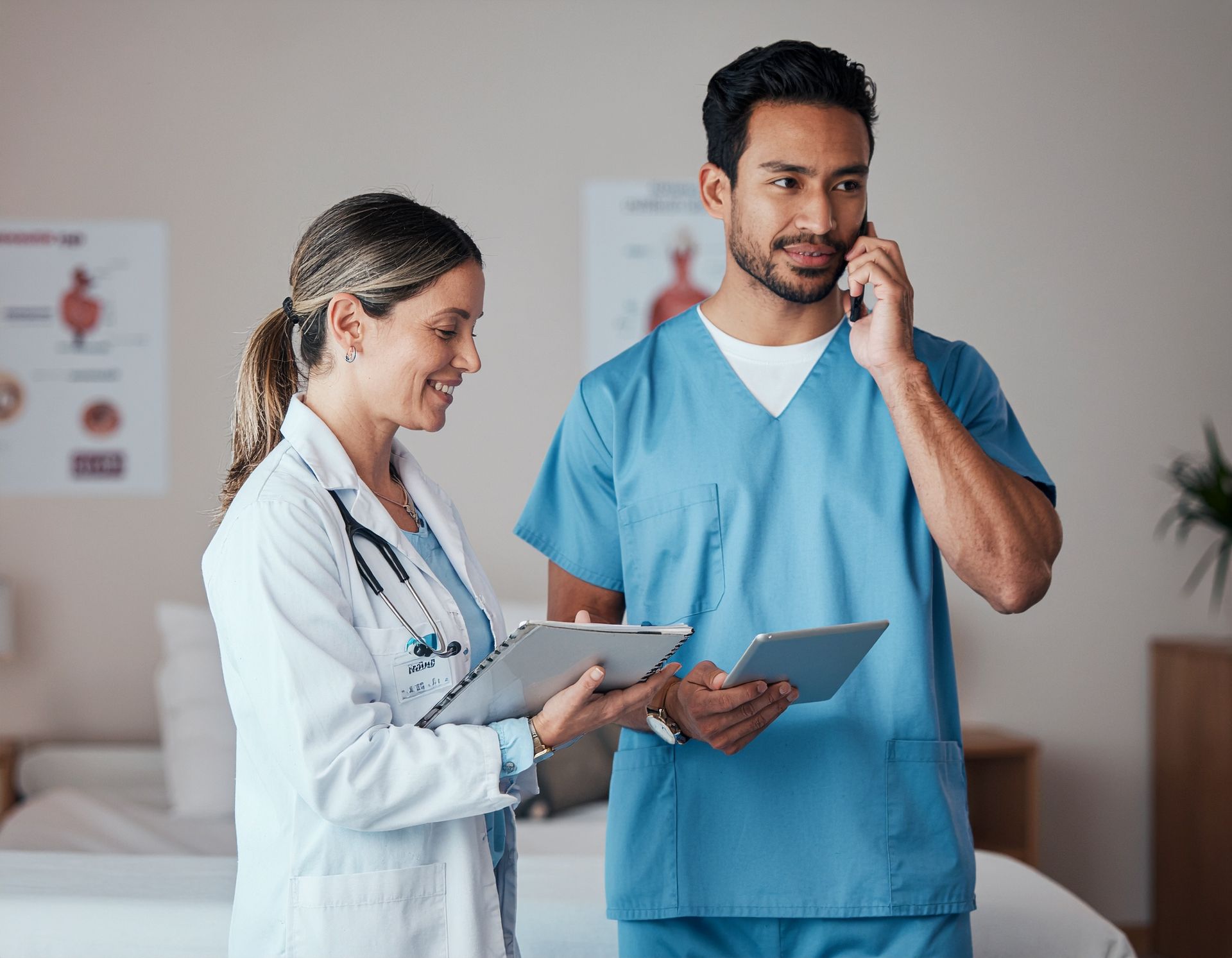 Medical professionals in scrubs and lab coat discussing paperwork, one on a phone in a clinic.