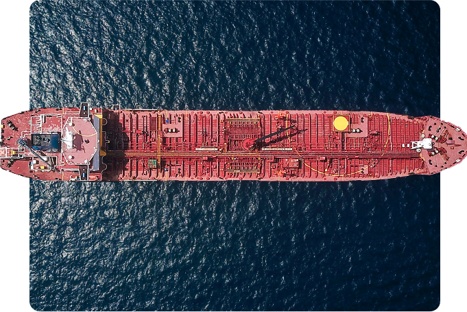 Overhead view of a red oil tanker ship sailing on blue ocean water.