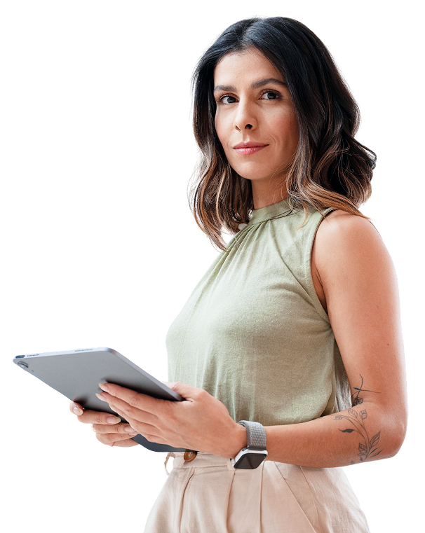 Woman holding tablet, wearing a green top and beige pants, looking at camera.