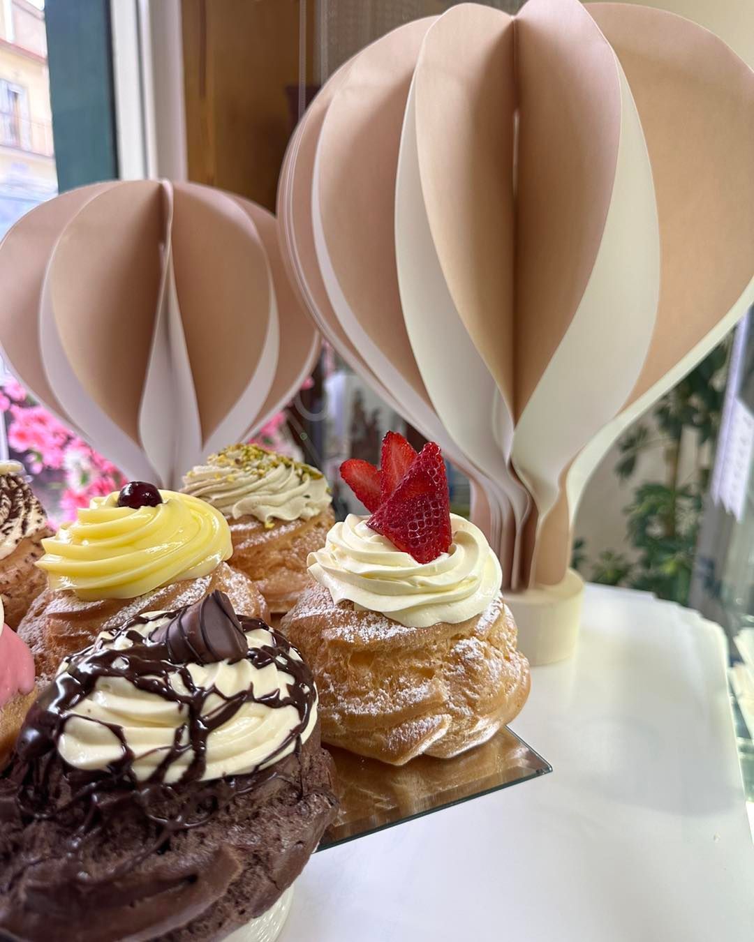 Un mucchio di cupcakes sono appoggiati su un tavolo con delle mongolfiere sullo sfondo.
