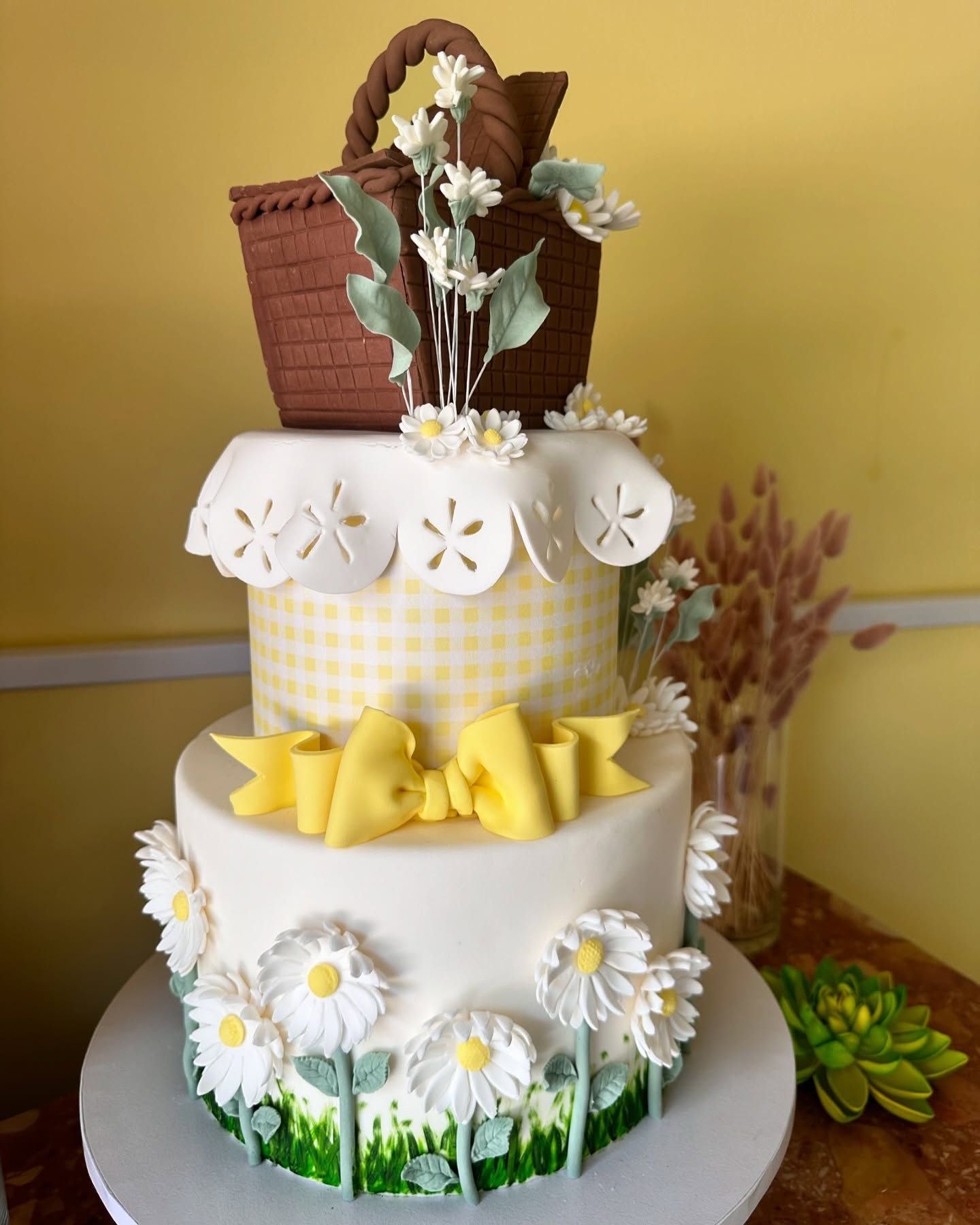 Una torta con margherite e un cestino da picnic sopra