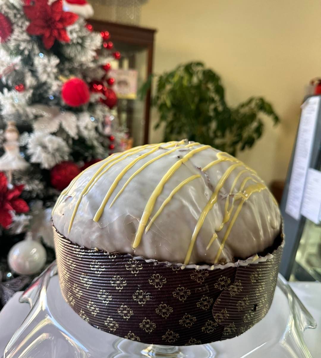 Una torta con glassa bianca e glassa gialla è appoggiata su un tavolo davanti all'albero di Natale.