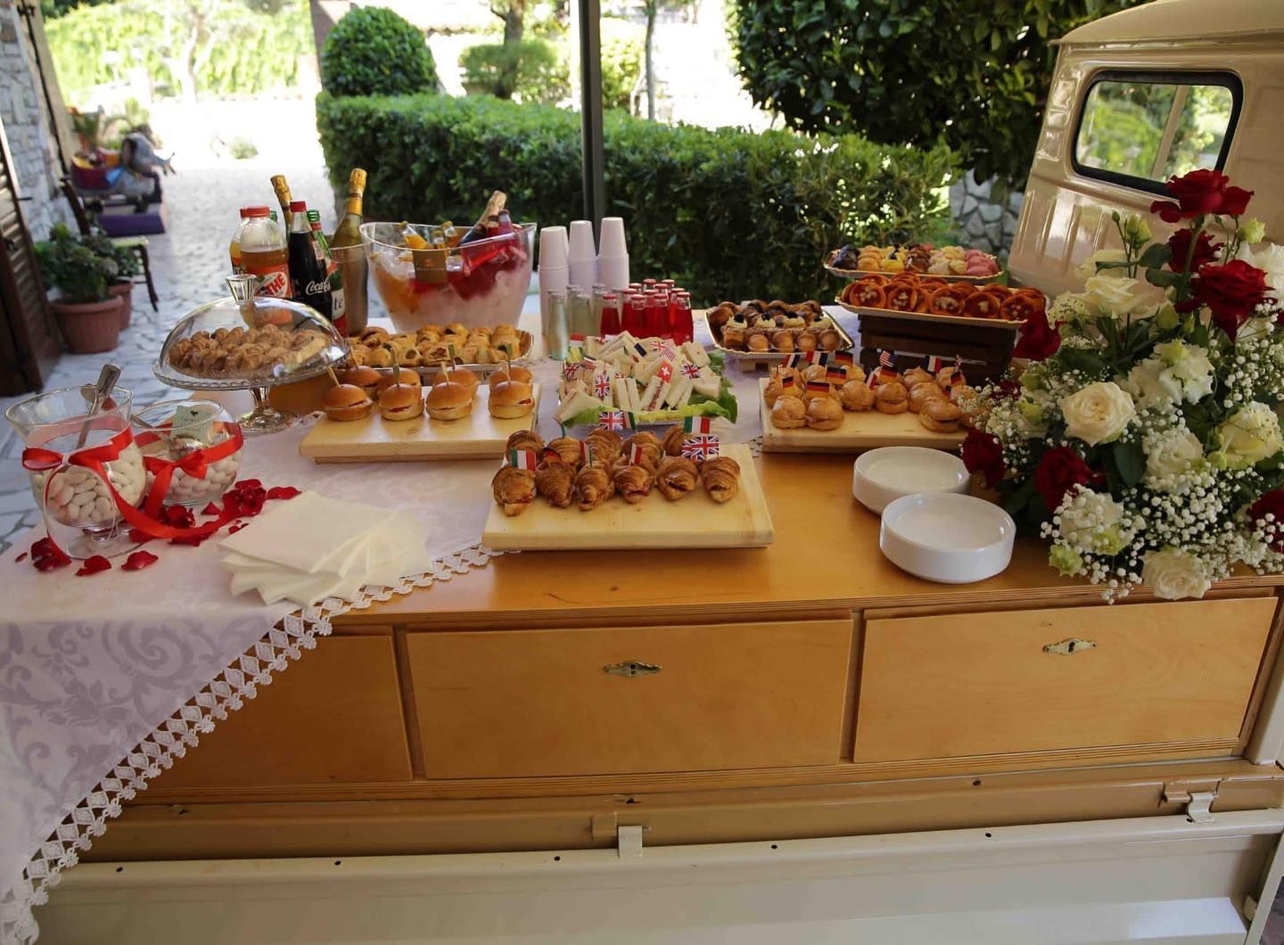 Un tavolo di legno con sopra piatti di cibo e fiori dell'ape car