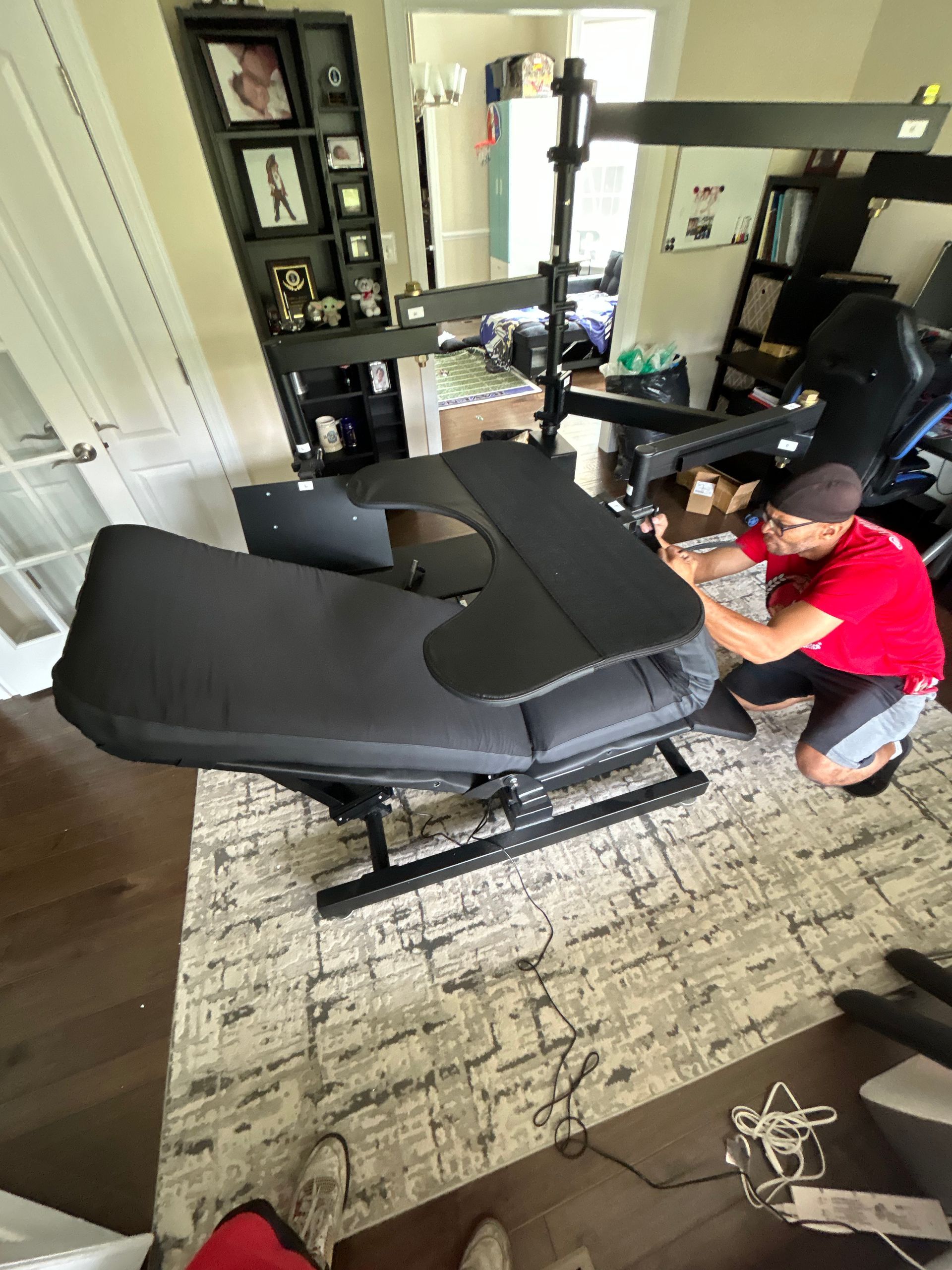 A man is kneeling down next to a chair in a living room.