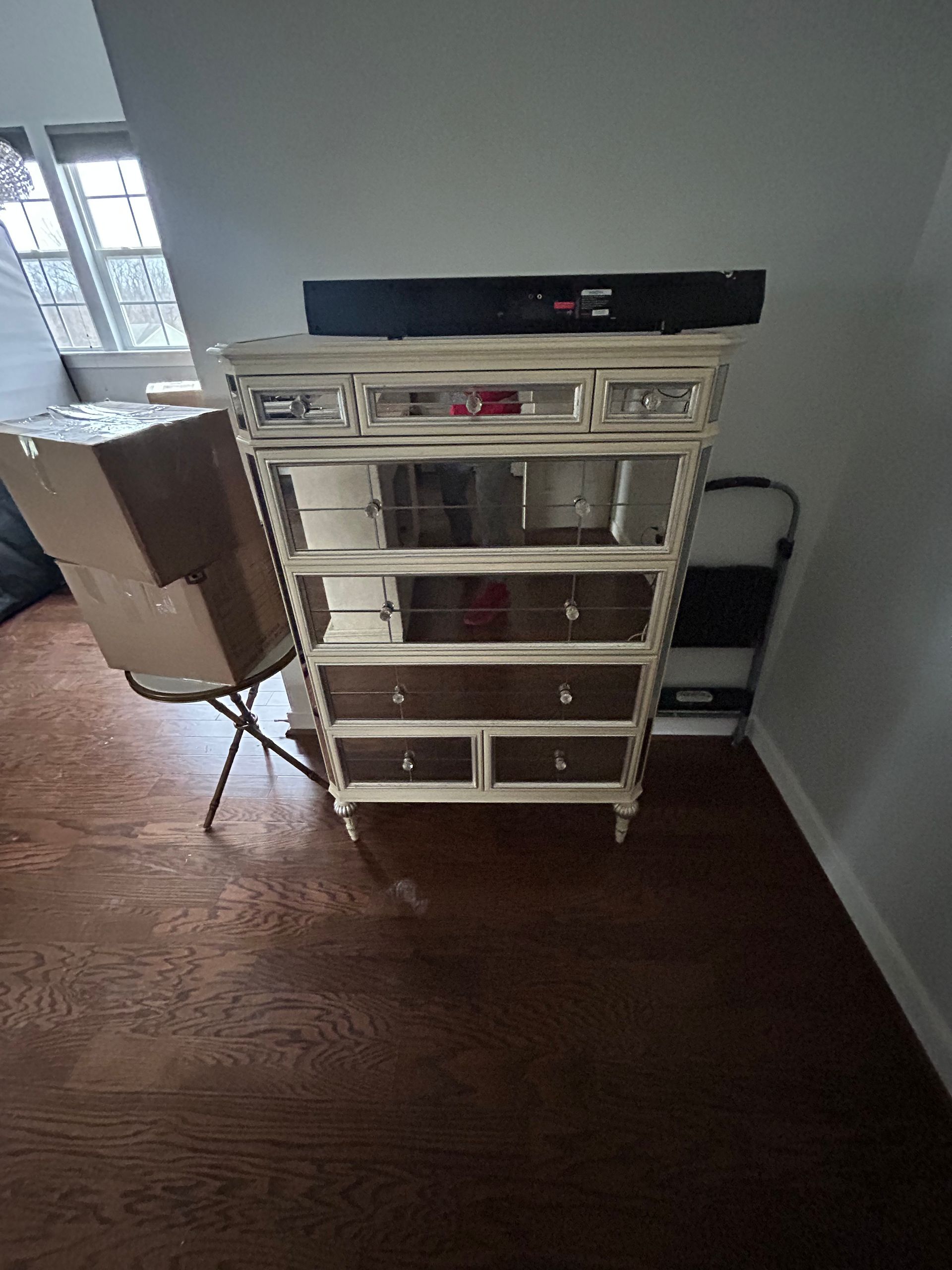 A white chest of drawers is sitting on a wooden floor in a room.