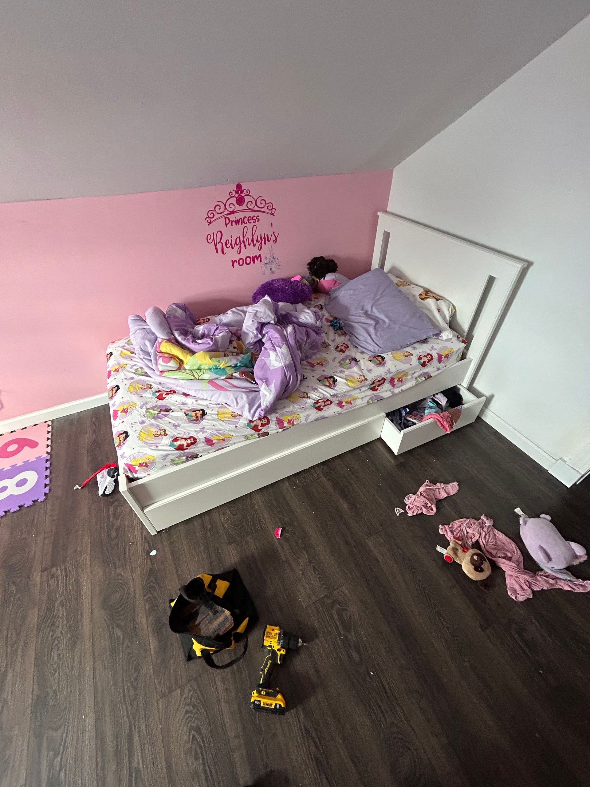 A child is laying on a bed in a messy room.