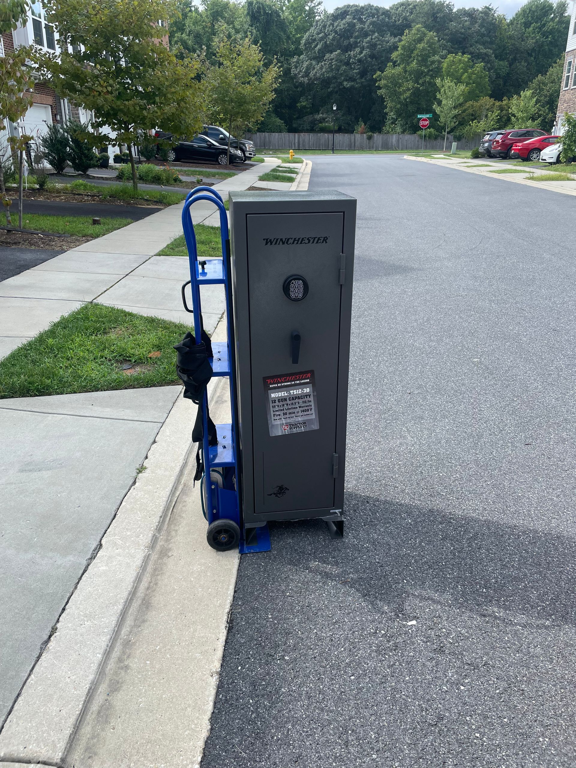 A safe is sitting on the side of the road next to a blue dolly.