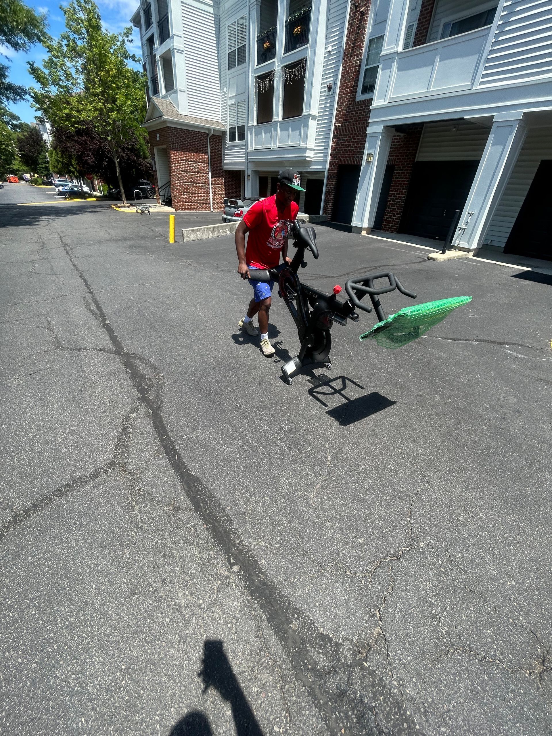 A man in a red shirt is walking down a street with a green bag.