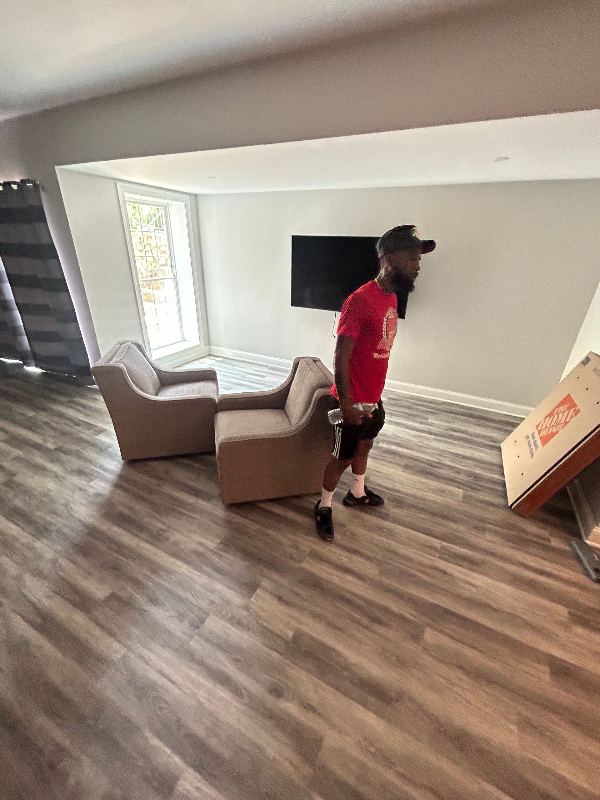 A man in a red shirt is standing in a living room.