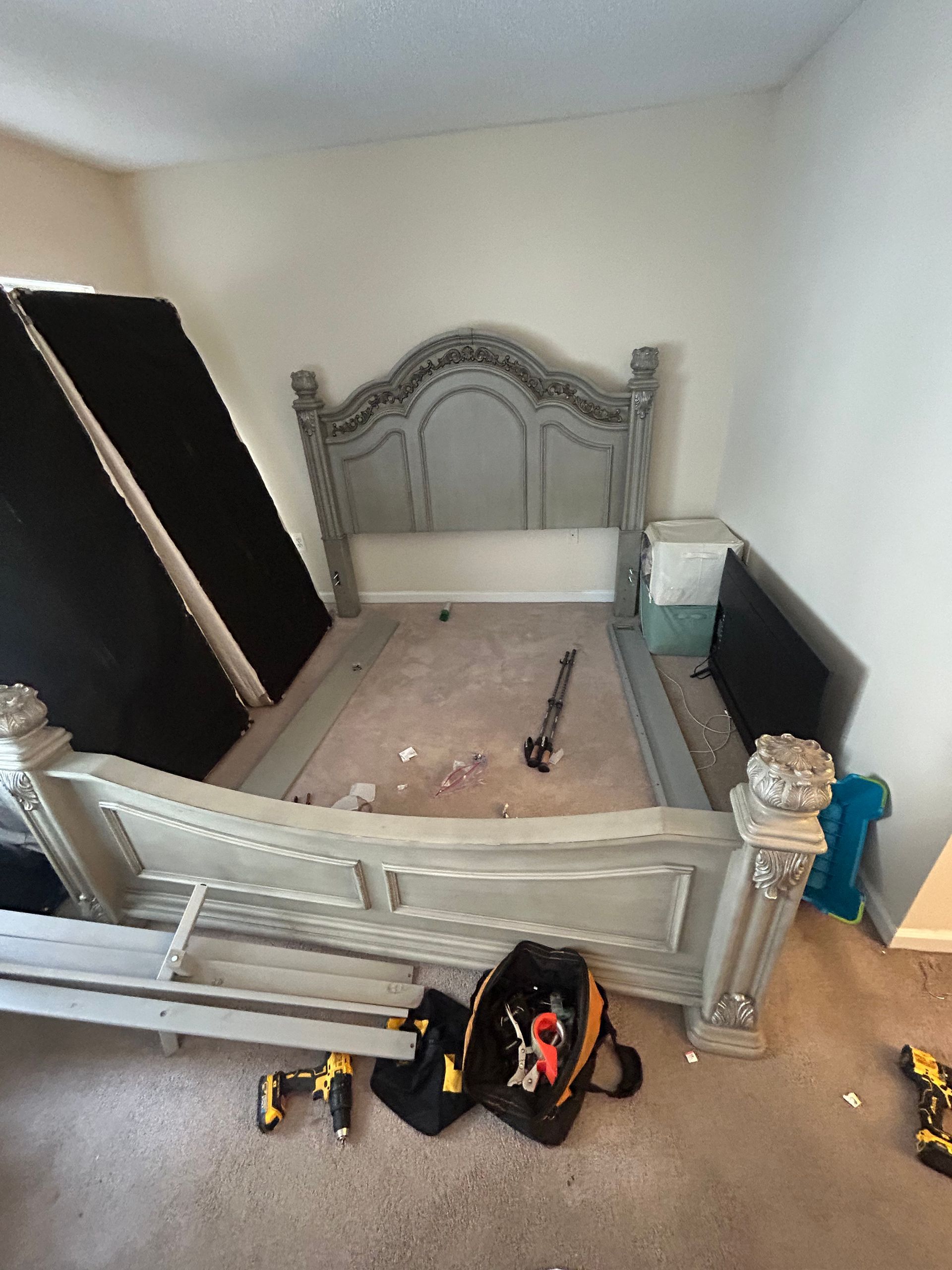 A bedroom with a bed and a bag of tools on the floor.