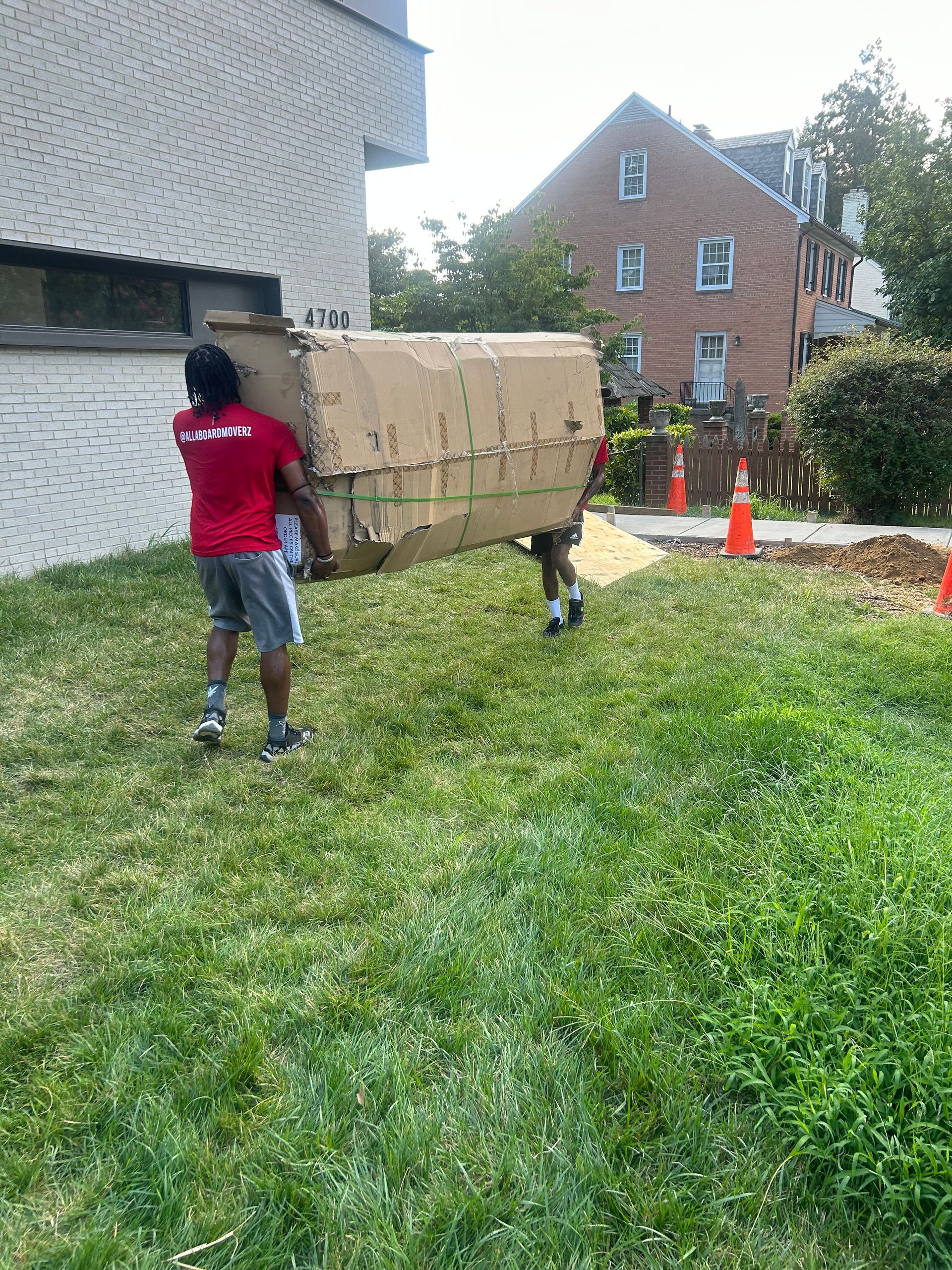 A man is carrying a large cardboard box on his back.