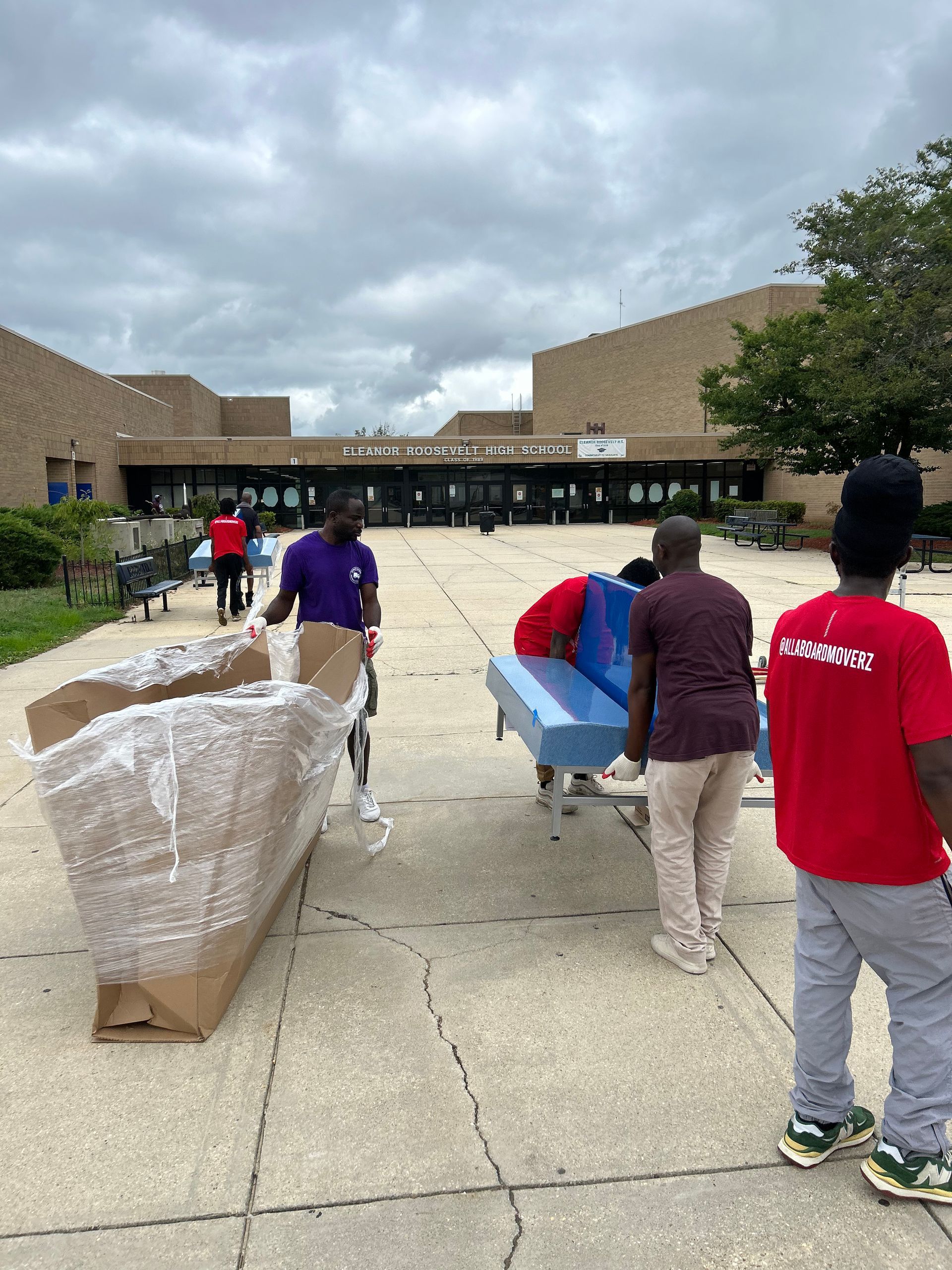 A group of people are moving a piano on a cart.