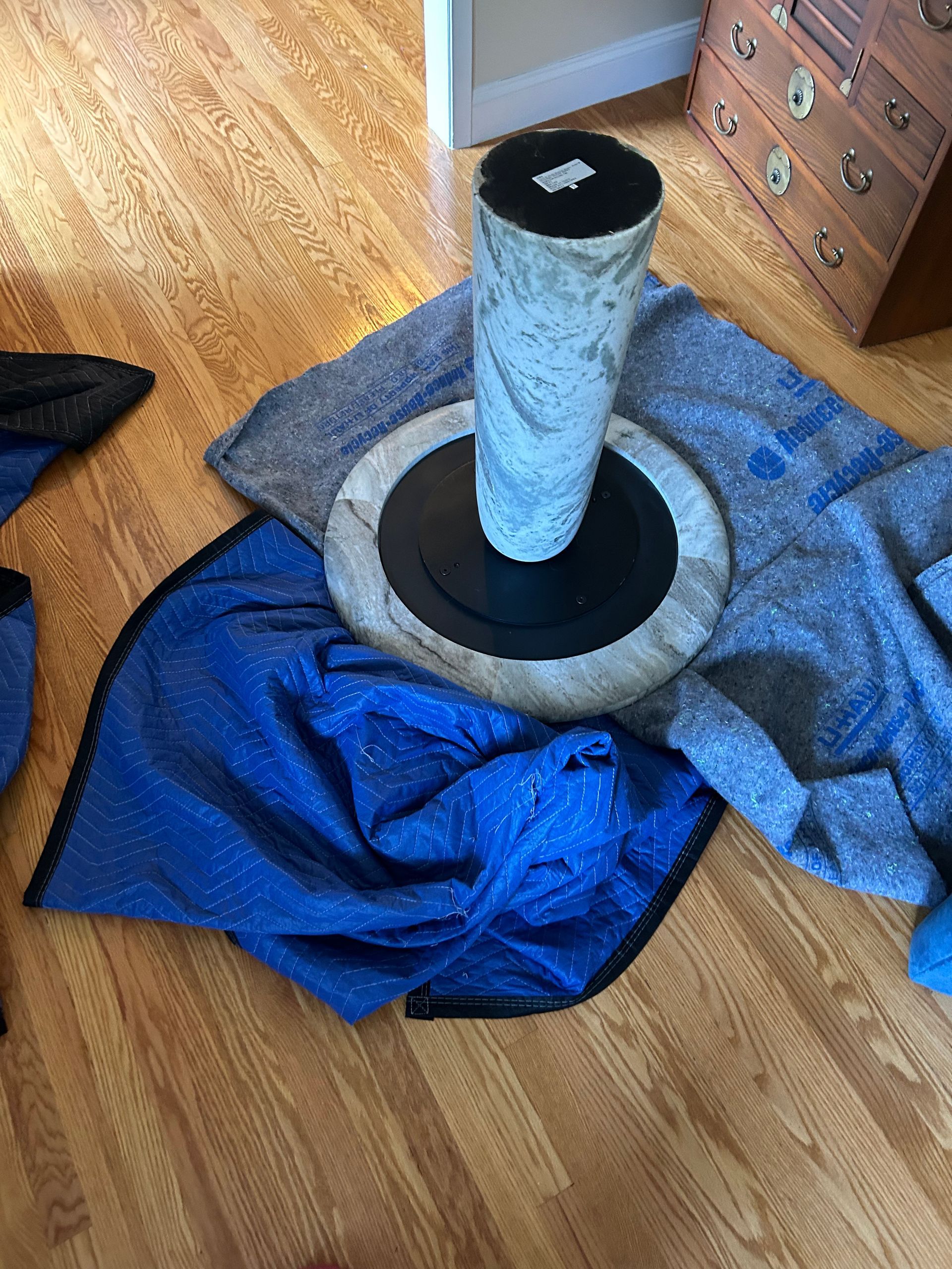 A cat tree is sitting on top of a blue blanket on a wooden floor.