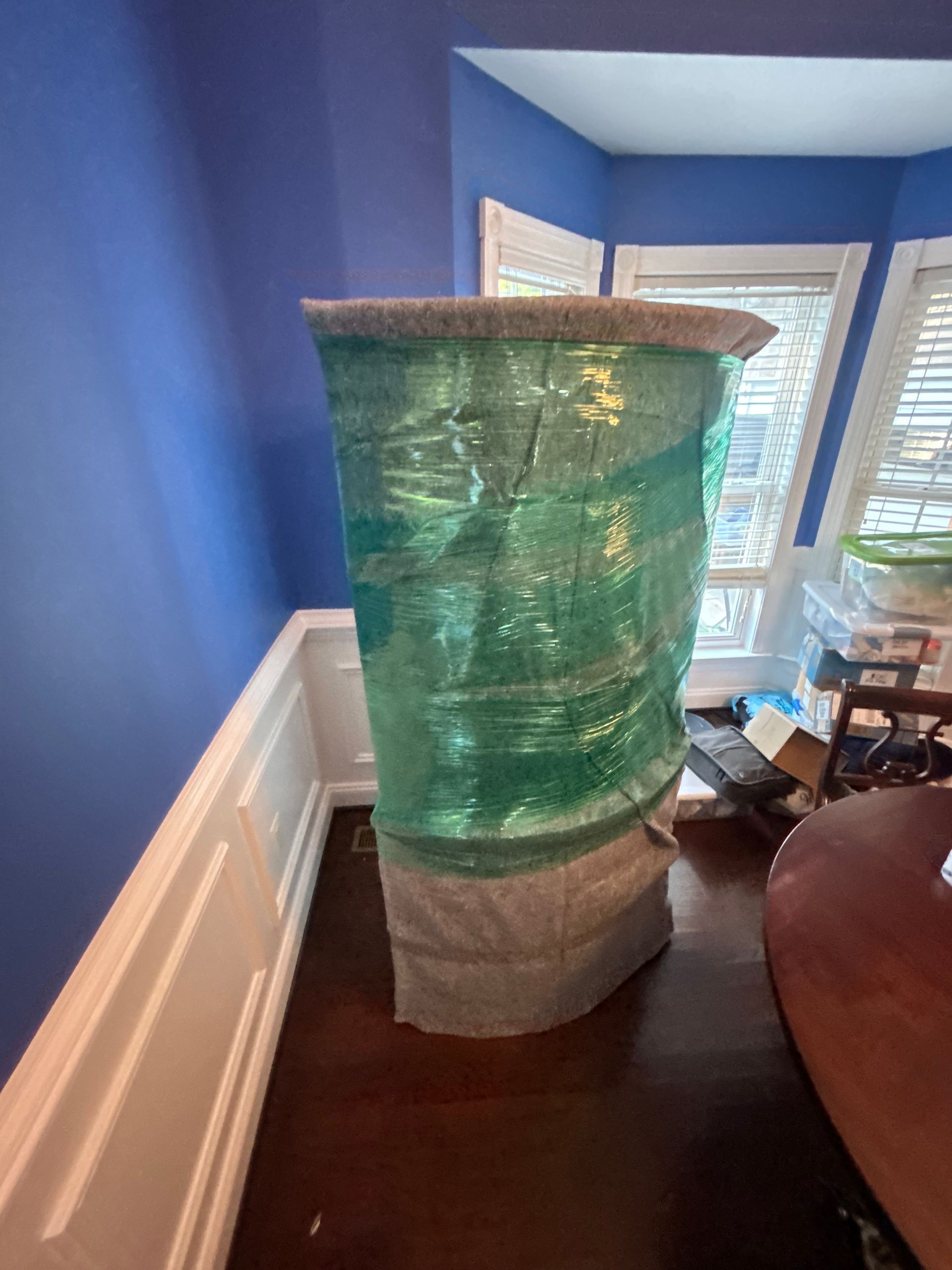 A large container is wrapped in plastic in a room.